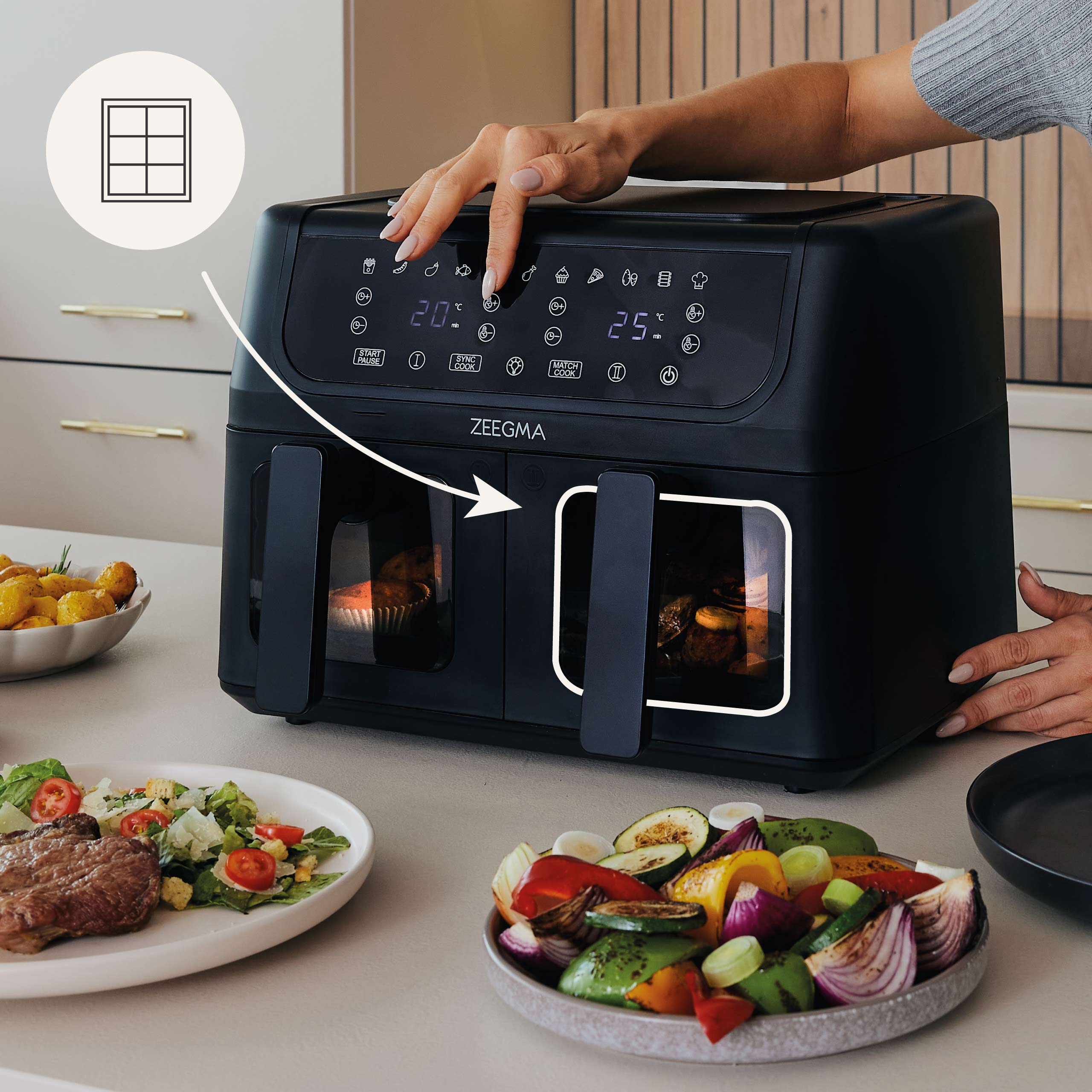 Czarna frytkownica Zeegma z jedzeniem w środku. Dłoń wskazuje na elementy sterujące i jedzenie w pobliżu.