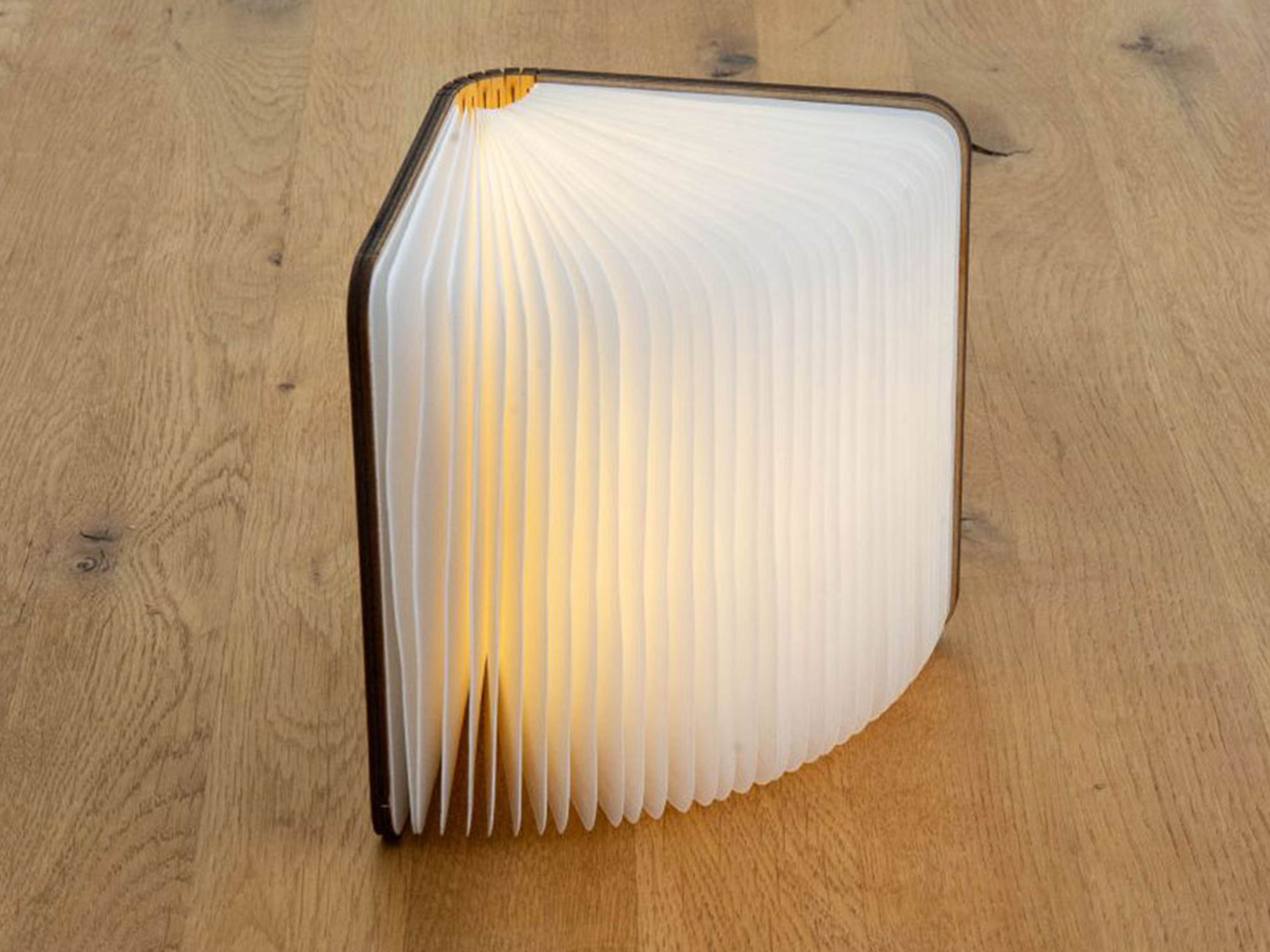 Una lampada a forma di libro che emette una luce calda e soffusa.