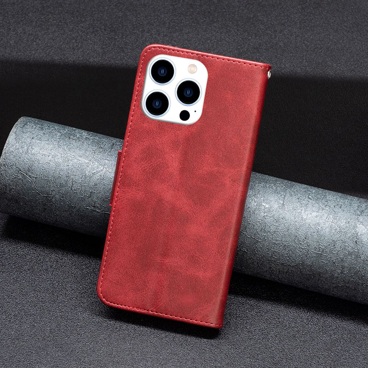 Rode leren telefoonhoes op een zwart oppervlak. De achterkant toont de camera en een kleine flap.