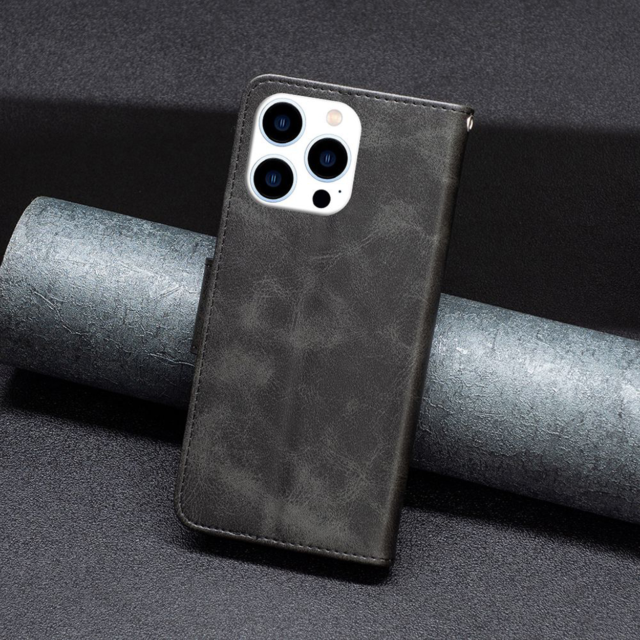 Donkergrijze telefoonhoes, met zichtbare camera. Op een donkere achtergrond.