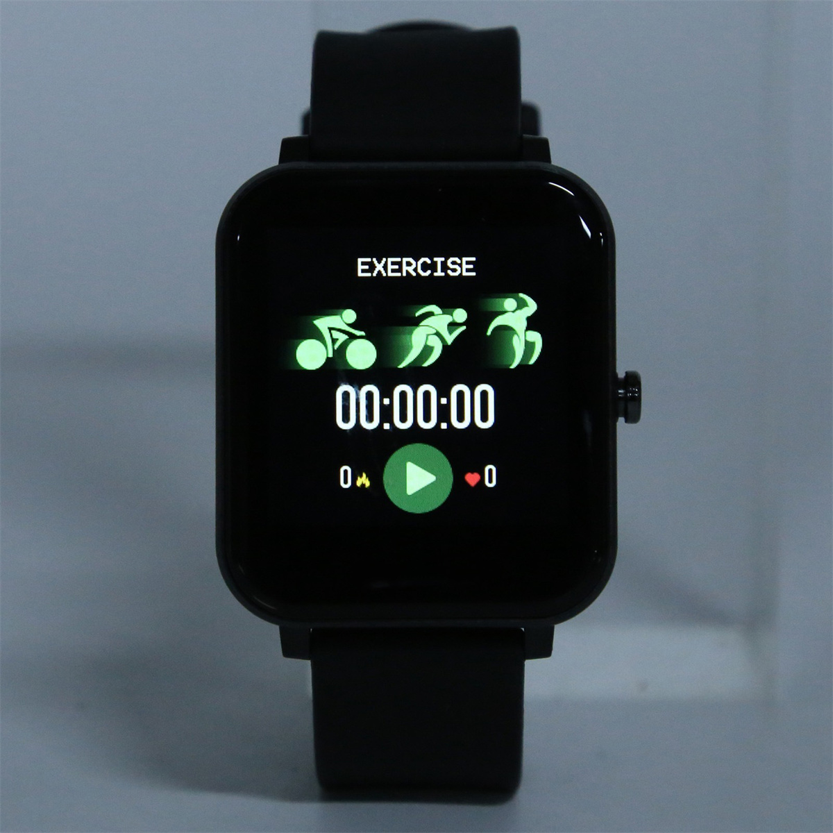Eine schwarze Smartwatch, die Trainingssymbole und die Zeit anzeigt. Die Uhr zeigt eine Wiedergabetaste und ein Herzsymbol.