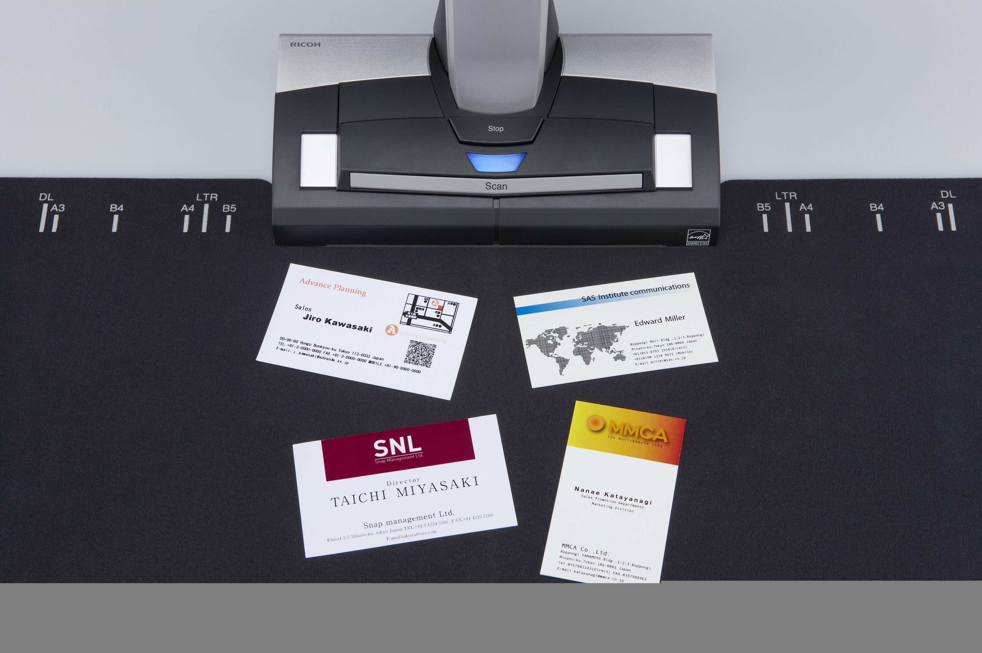 Wizytówki na skanerze. Różne karty z logo i tekstem na czarnej powierzchni.