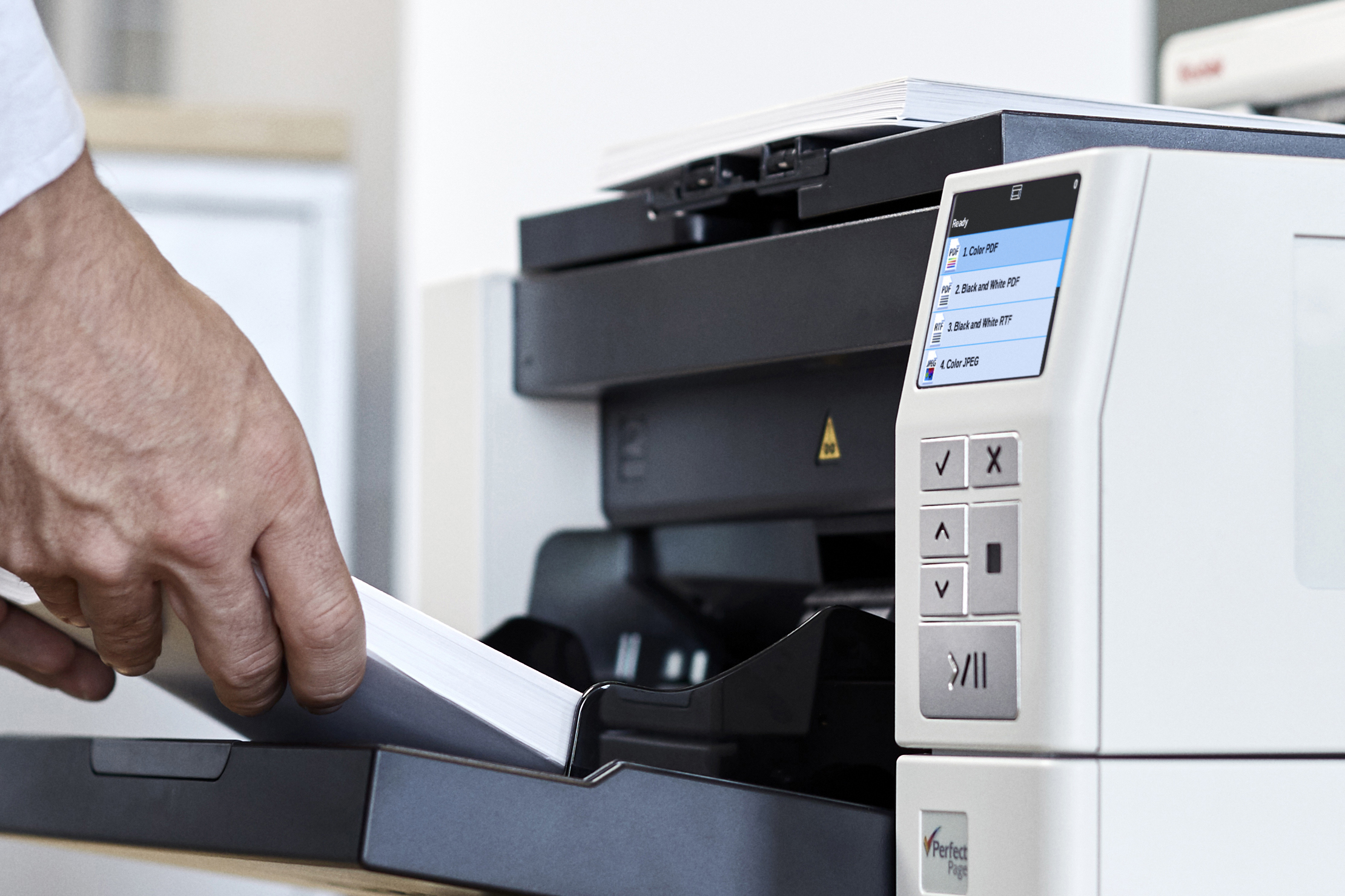 Mano che carica carta in uno scanner. Lo scanner mostra le opzioni sul suo schermo.