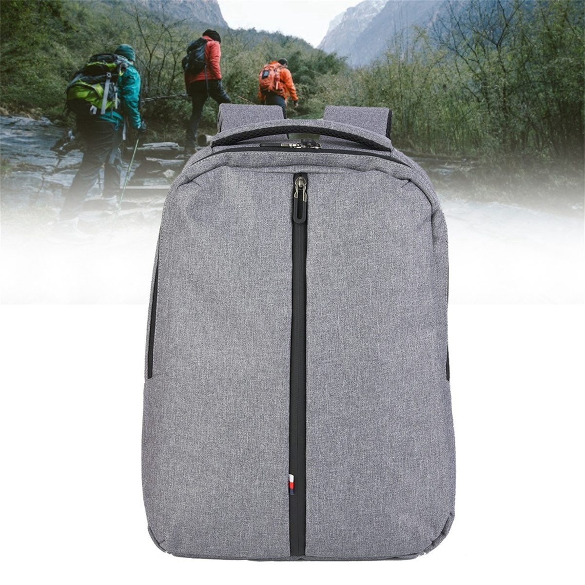 Grauer Rucksack mit schwarzem Reißverschluss, im Hintergrund wandernde Menschen. Fokus auf der Vorderseite der Tasche.