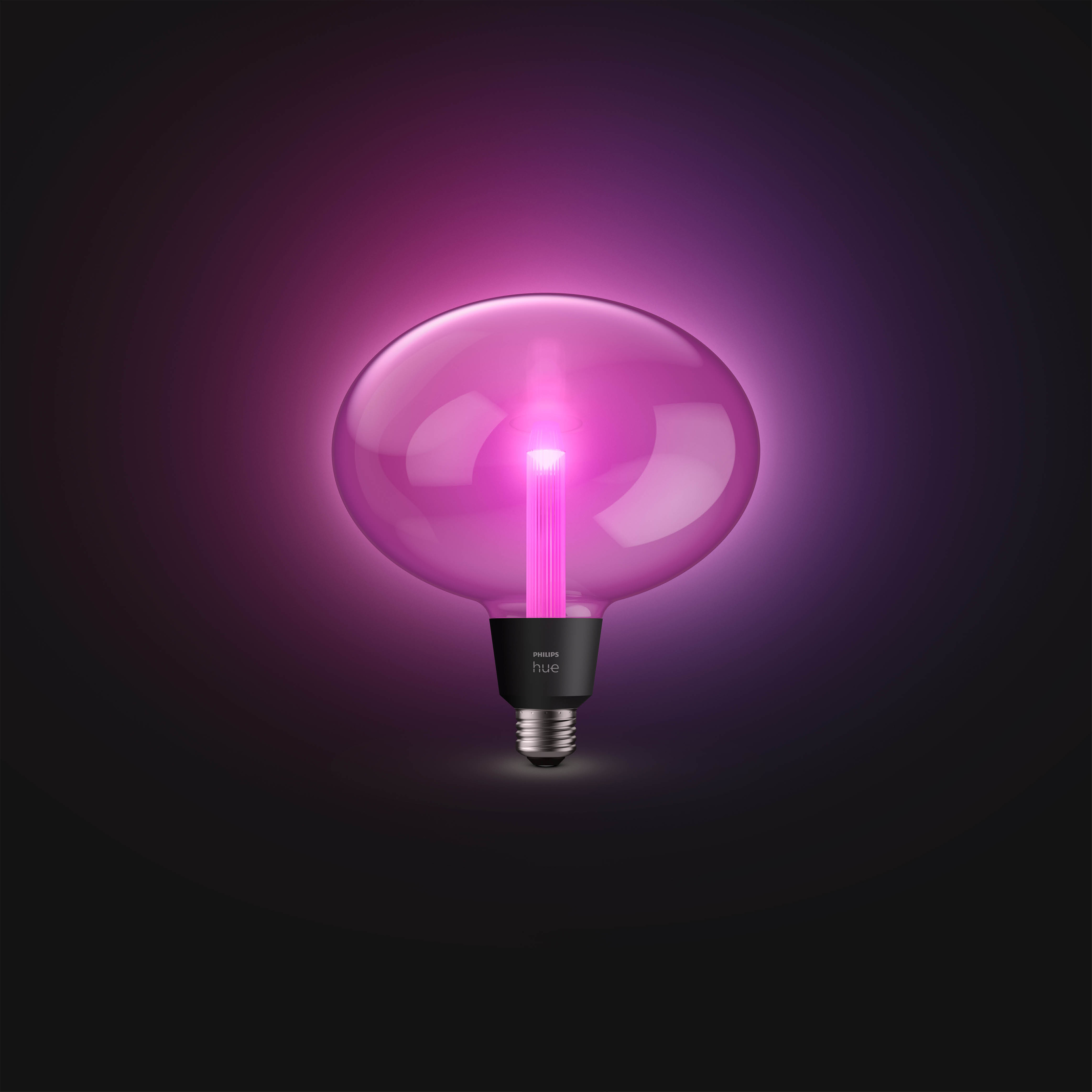 Żarówka Philips Hue. Okrągłe, różowe światło, z czarną podstawą, na ciemnym tle.