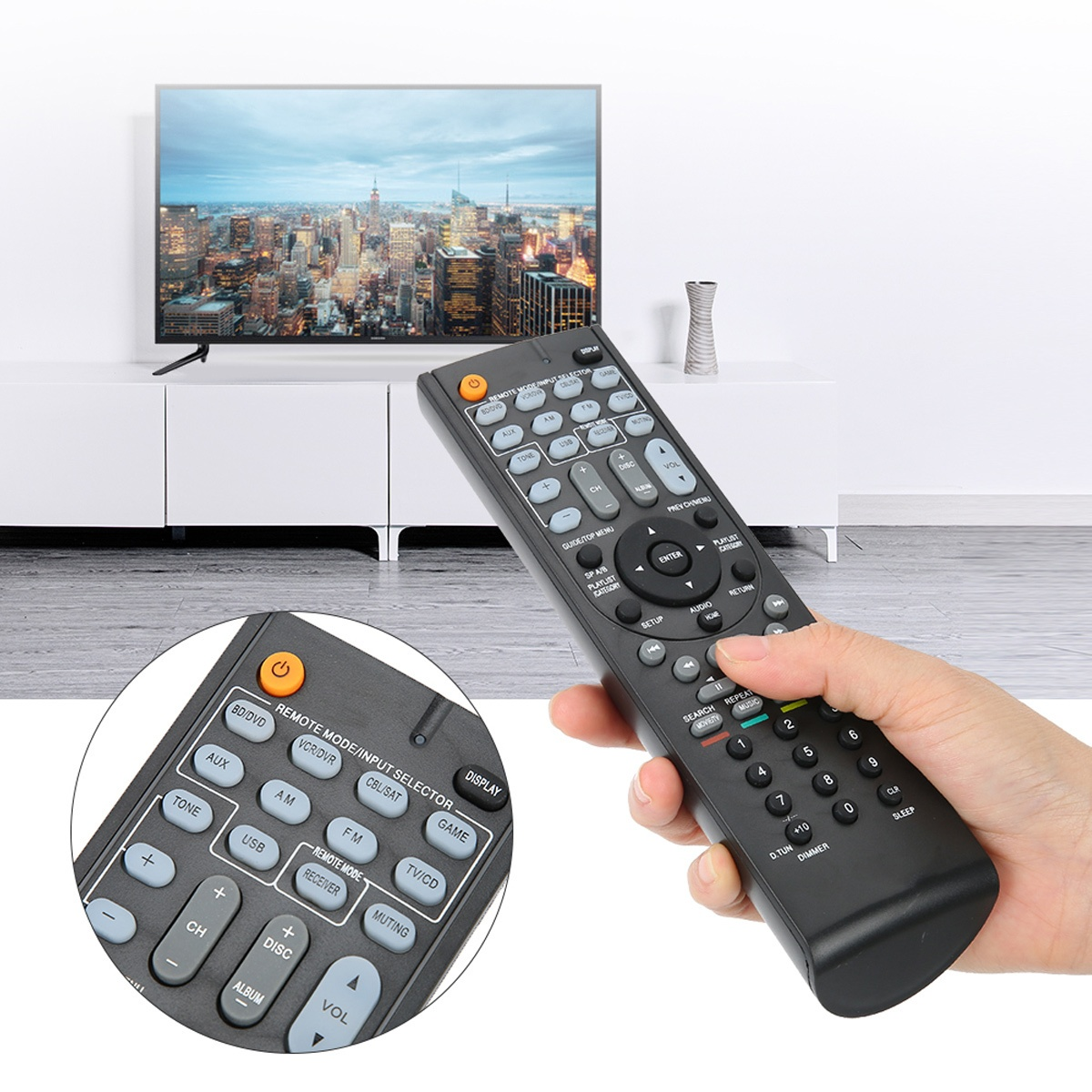 Schwarze Fernbedienung in der Hand, Fernseher im Hintergrund. Nahaufnahme zeigt Tasten.
