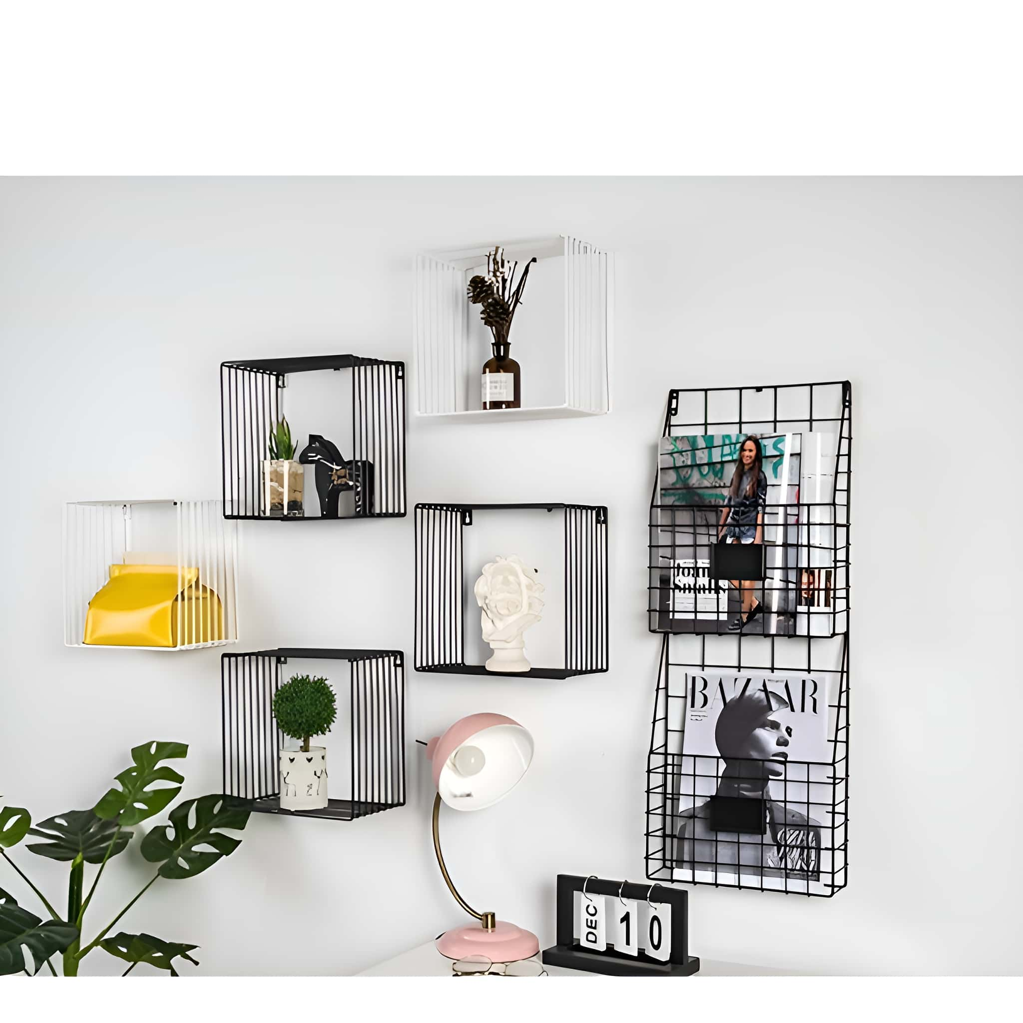 Weiße Wand mit Drahtregalen, Dekoration, Pflanzen, Zeitschriften und einer rosa Lampe.