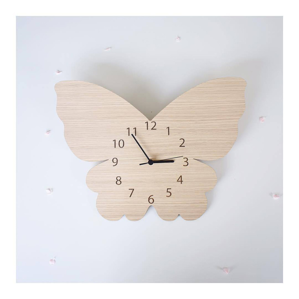Schmetterlingsförmige Holzuhr an weißer Wand. Zeiger auf der Uhr zeigen die Zeit.