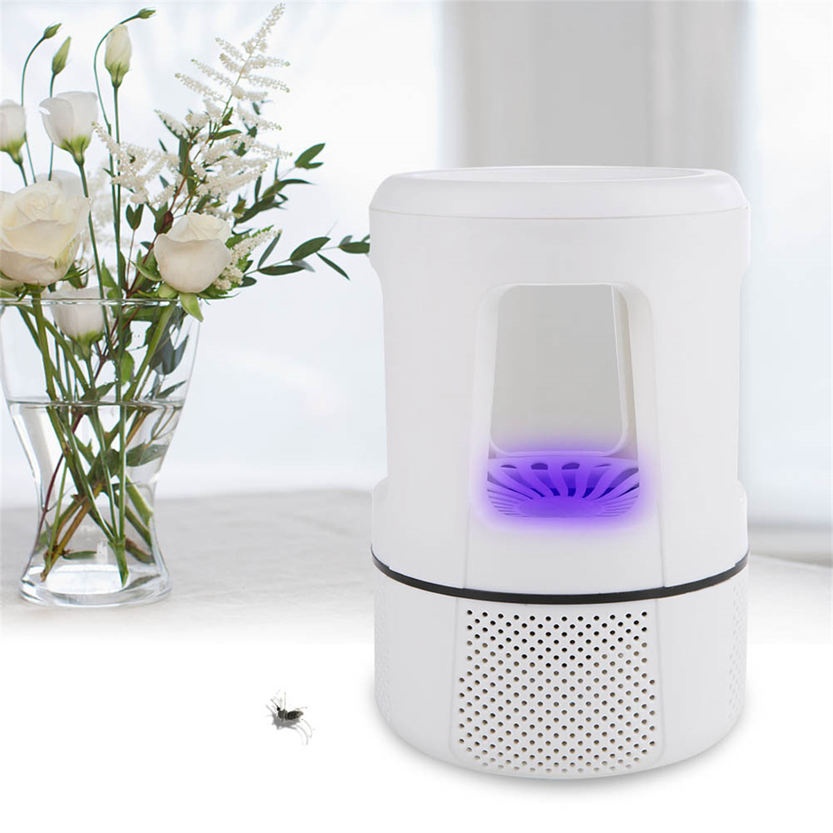 Weiße Insektenvernichter mit lila Licht. Blumen in Vase daneben. Eine Mücke fliegt in der Nähe.