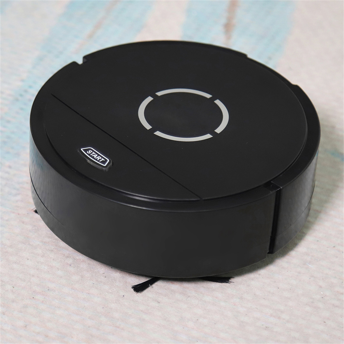 Schwarzer Roboter-Staubsauger auf einer Oberfläche. Der Reiniger ist rund, mit Startknopf und Licht.