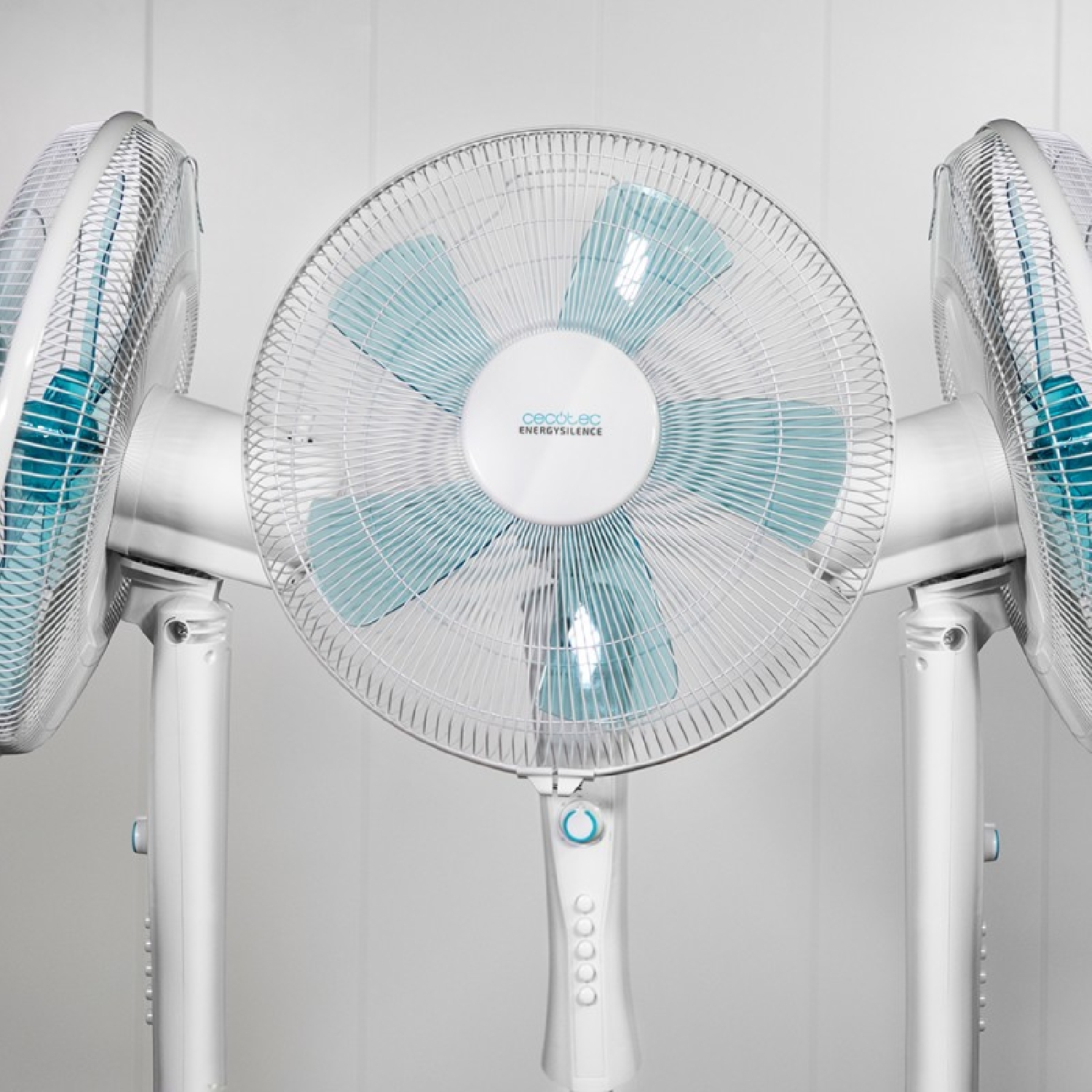 Tres ventiladores blancos con aspas azules están uno al lado del otro. Sobre fondo blanco.