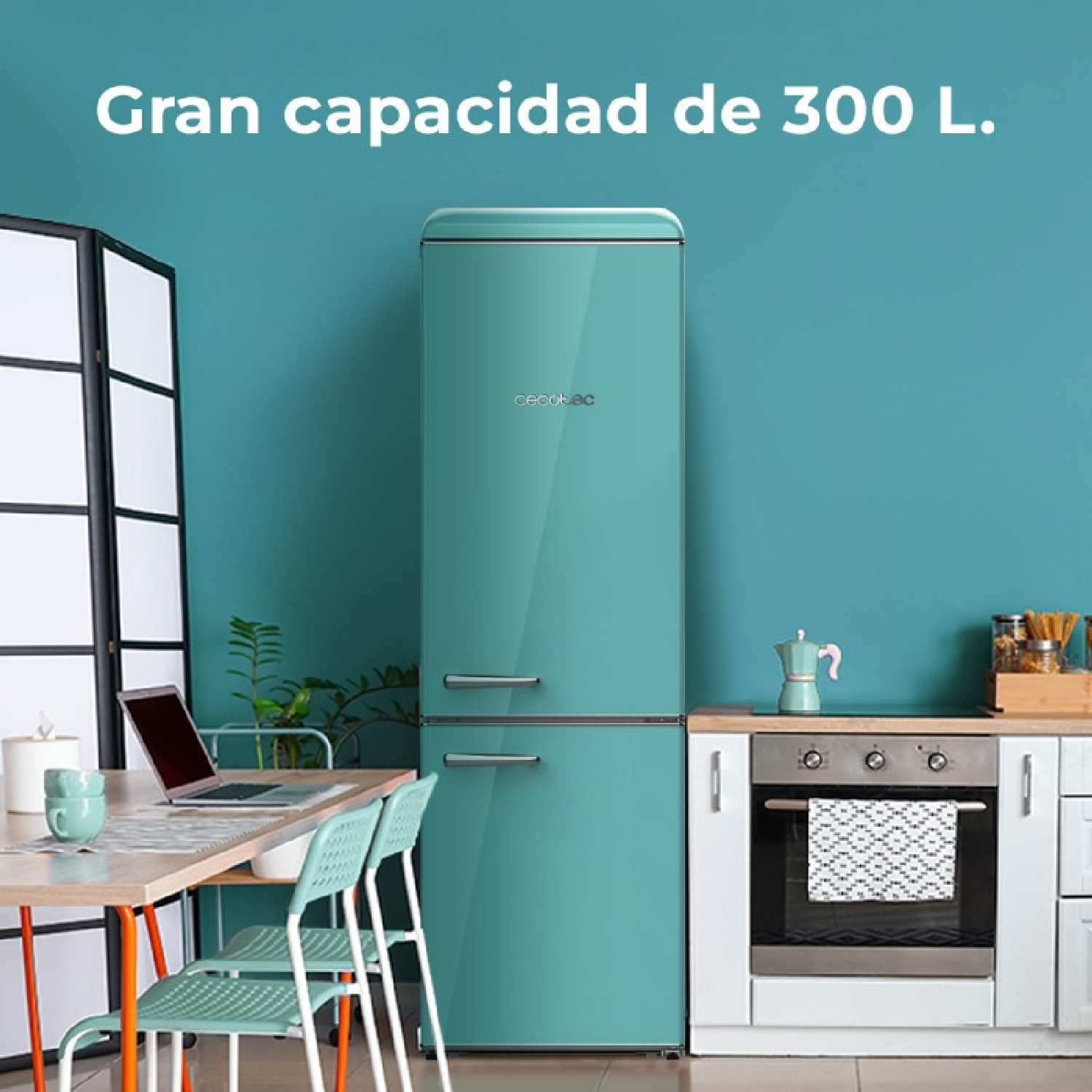 Refrigerador retro turquesa en una cocina. Hay una computadora portátil, una mesa y una silla cerca.