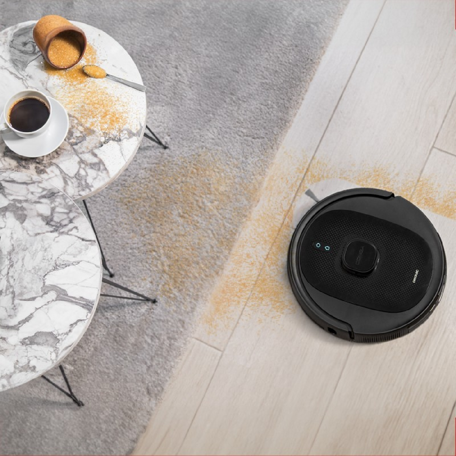 Aspirapolvere robot nero che pulisce un pavimento con granelli di zucchero versati.
