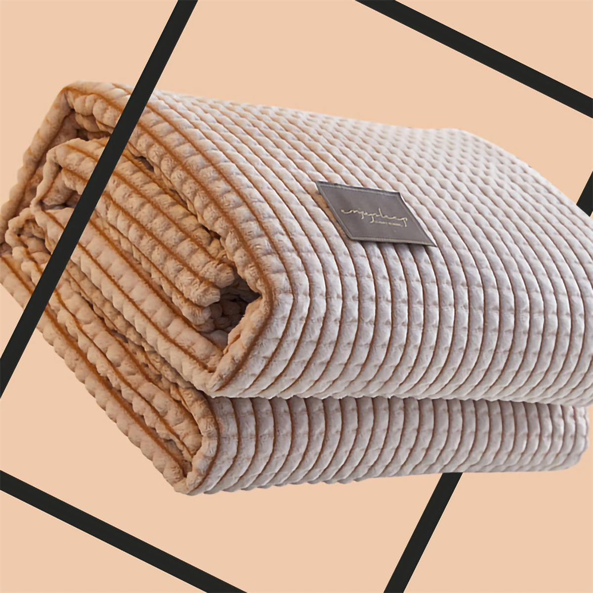 Gefaltete, beige Corddecke mit kleinem Etikett vor pfirsichfarbenem Hintergrund.