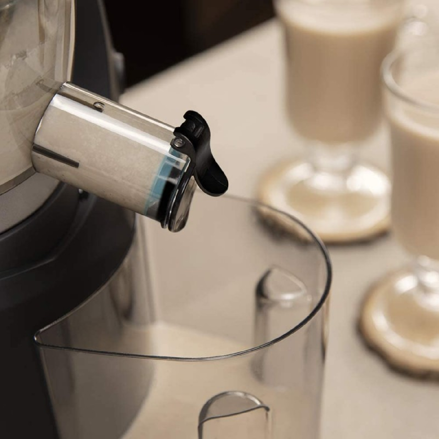 Macchina che eroga liquido in un contenitore. Due bicchieri con liquido simile sullo sfondo.