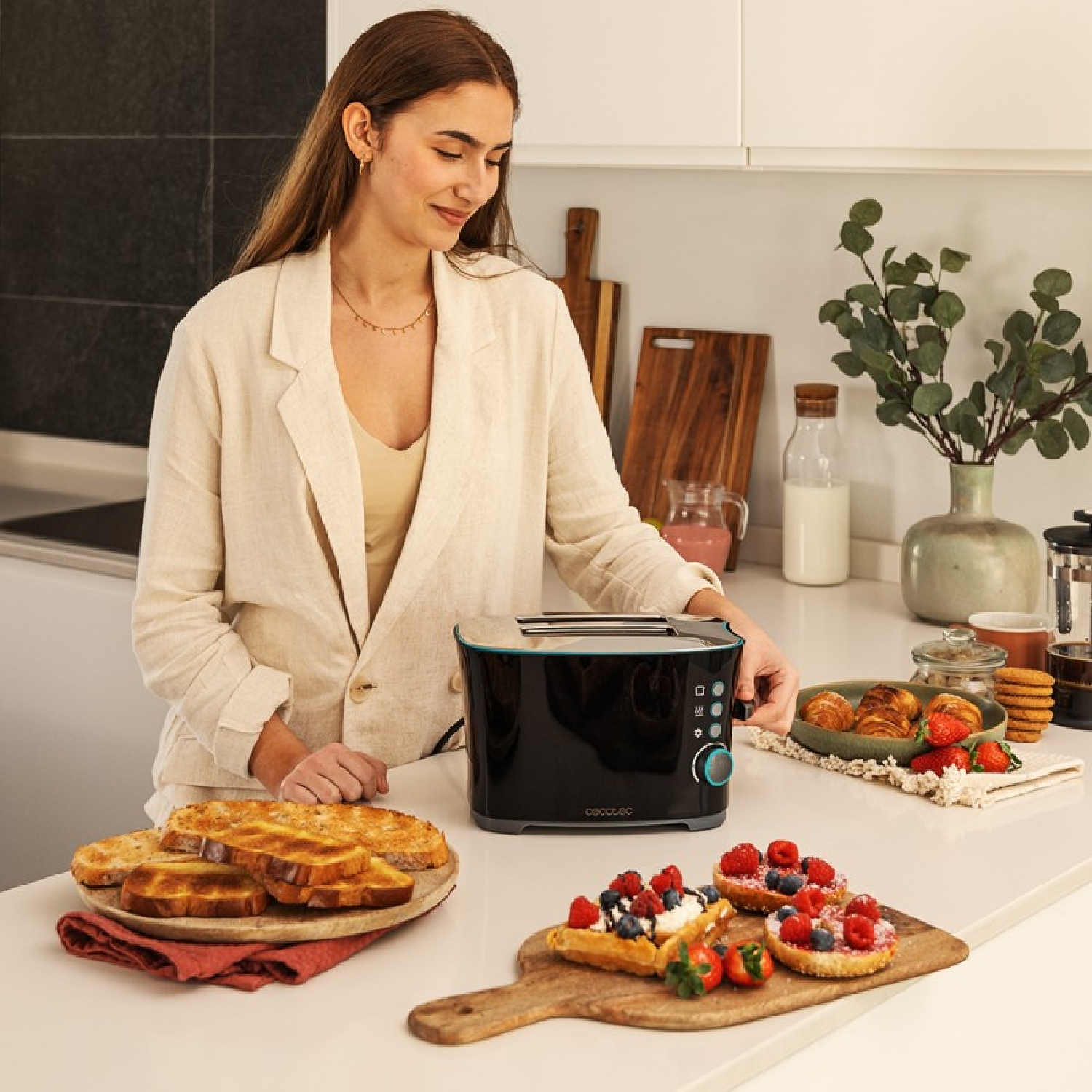 Una donna usa un tostapane nero, con pane e pasticcini sul bancone della cucina.