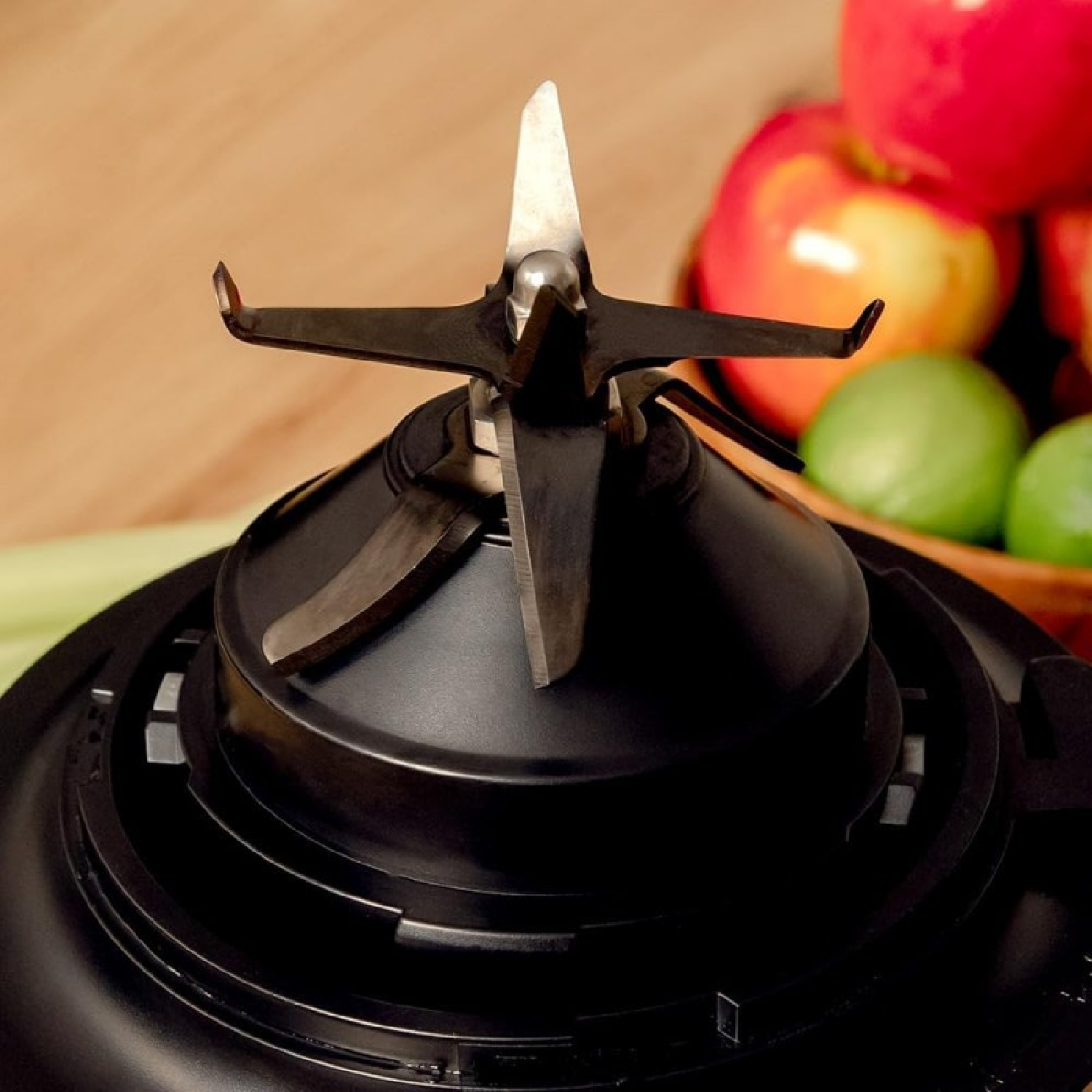 Nahaufnahme einer Mixerklingeneinheit mit Obst im Hintergrund.