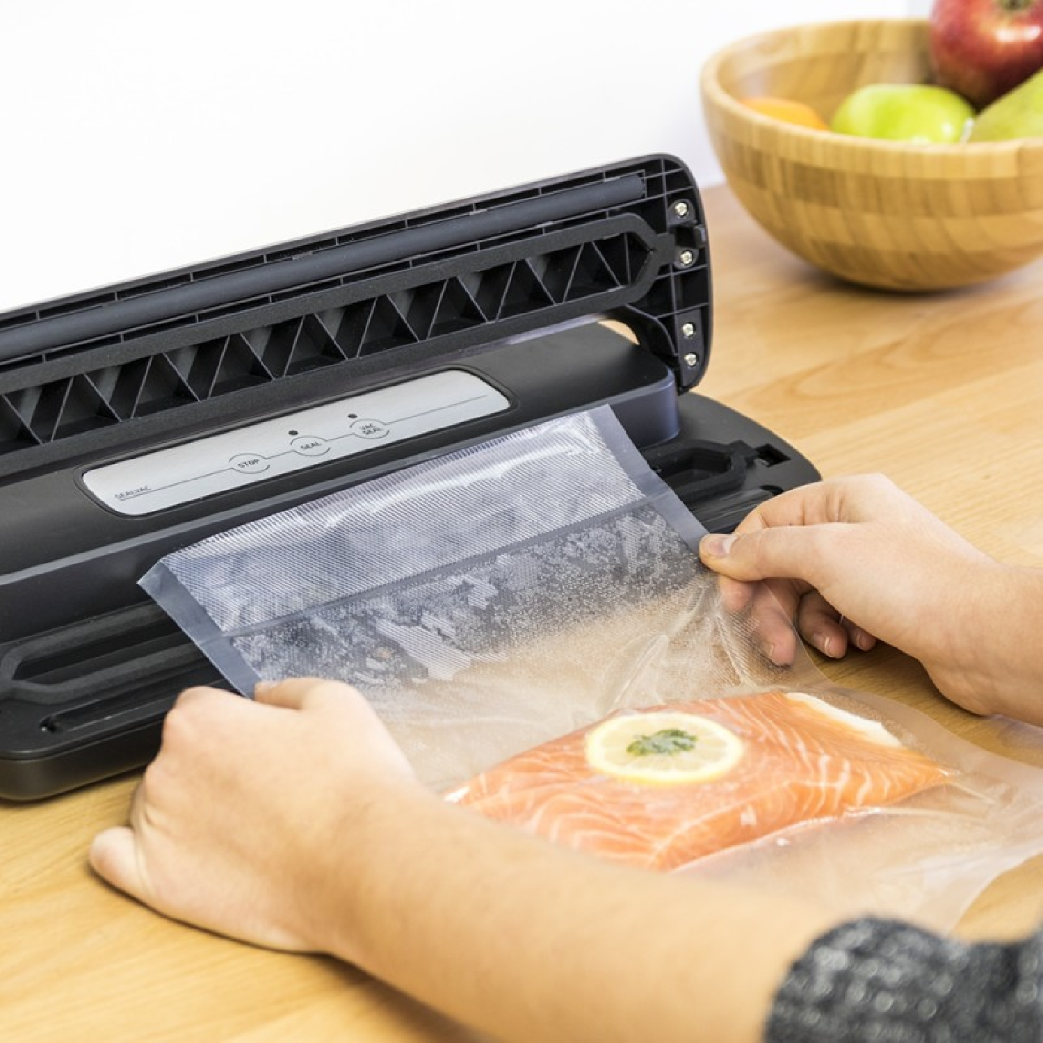 Una persona está utilizando una selladora al vacío para sellar un trozo de salmón.