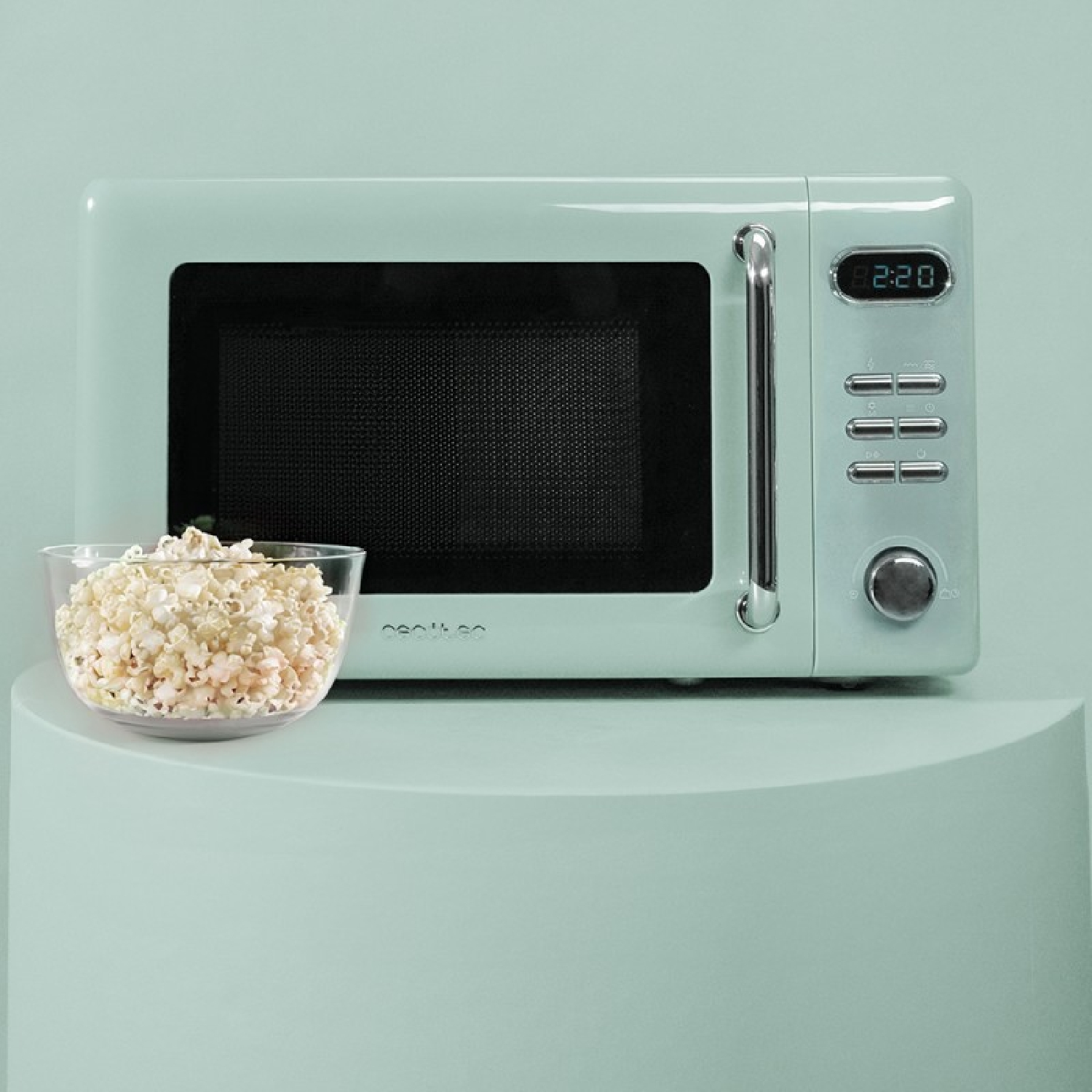 Miętowy mikrofalówka z miską popcornu z przodu. Posiada cyfrowy zegar i przyciski sterowania.