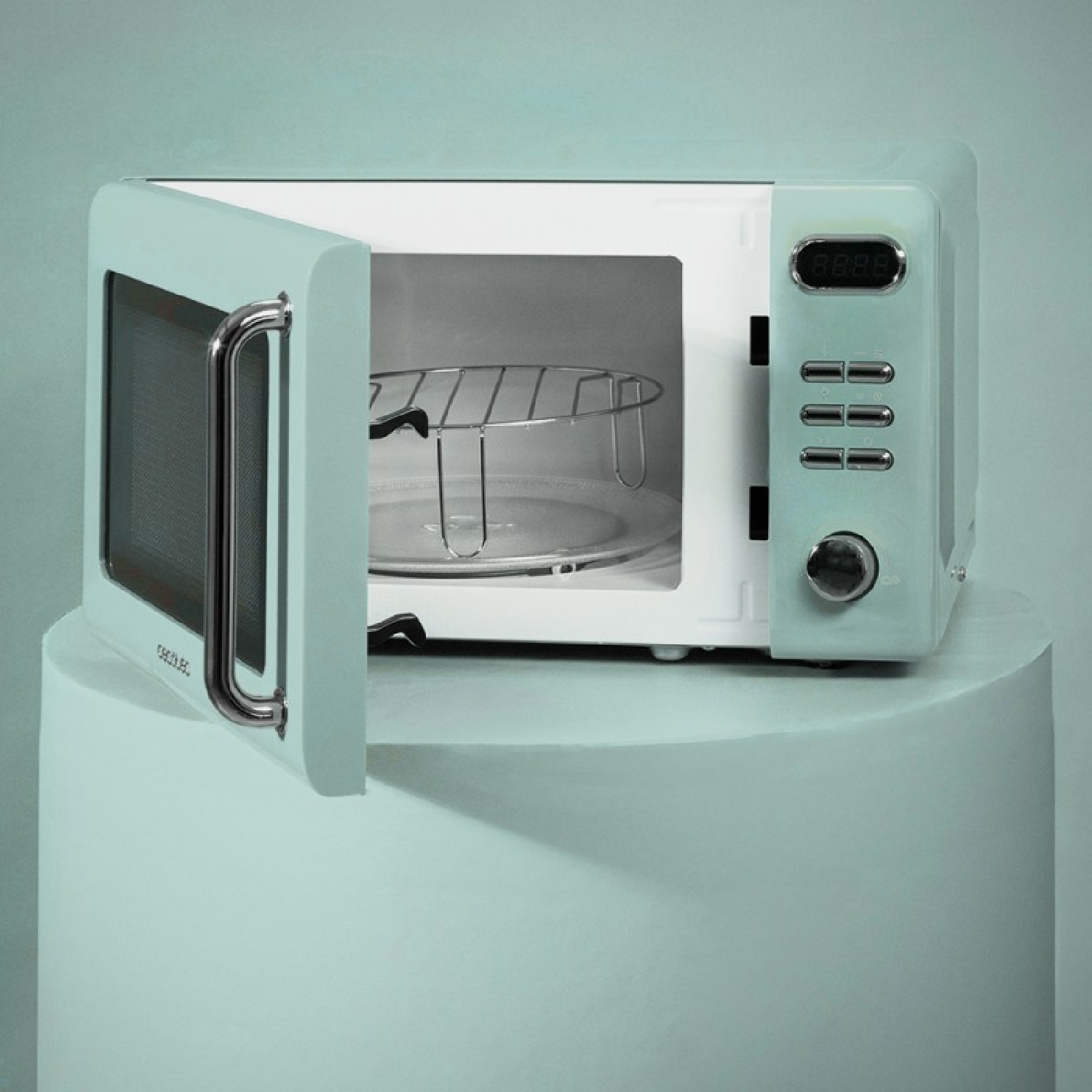 Un forno a microonde verde menta in stile vintage con la porta aperta, che rivela l'interno e un piatto di vetro.