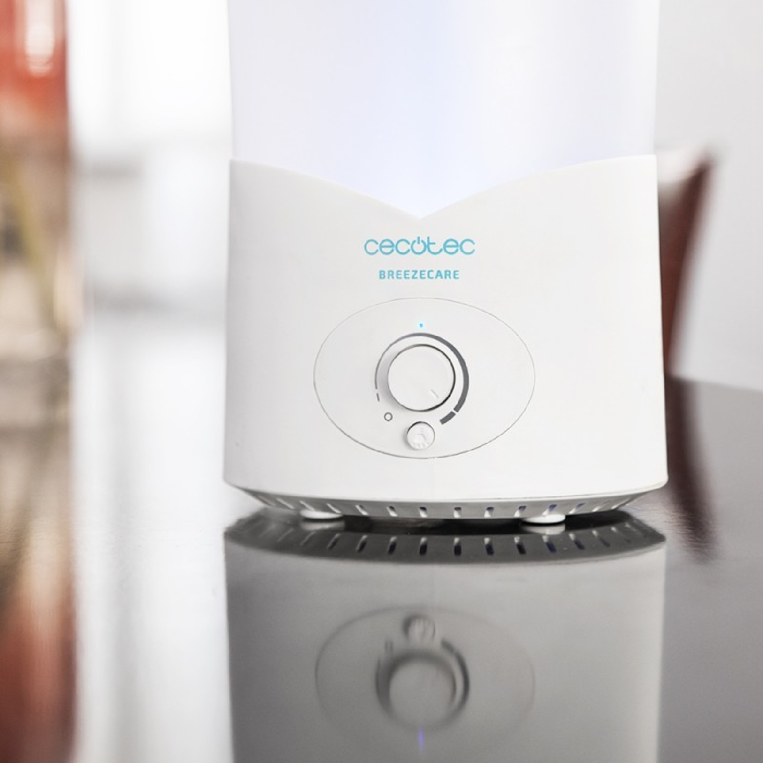 Biały oczyszczacz powietrza z pokrętłem, odbijający się na błyszczącej czarnej powierzchni.