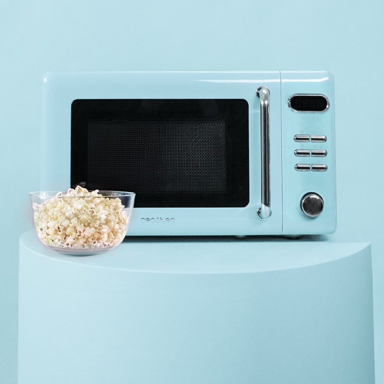 Jasnoniebieska kuchenka mikrofalowa z miską popcornu i niebieskim stojakiem.