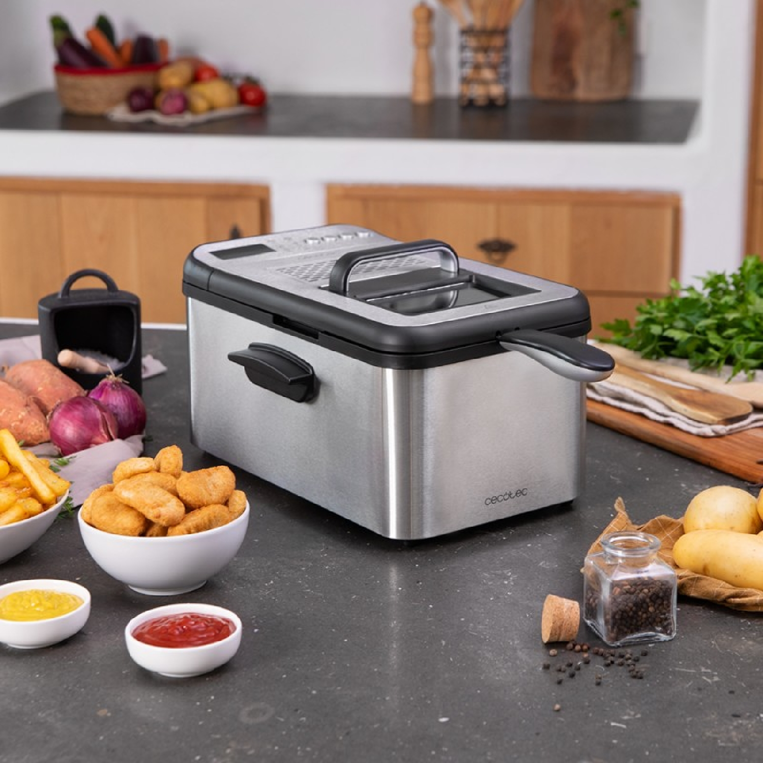 Srebrno-czarna frytkownica z jedzeniem, przyprawami i składnikami na blacie.