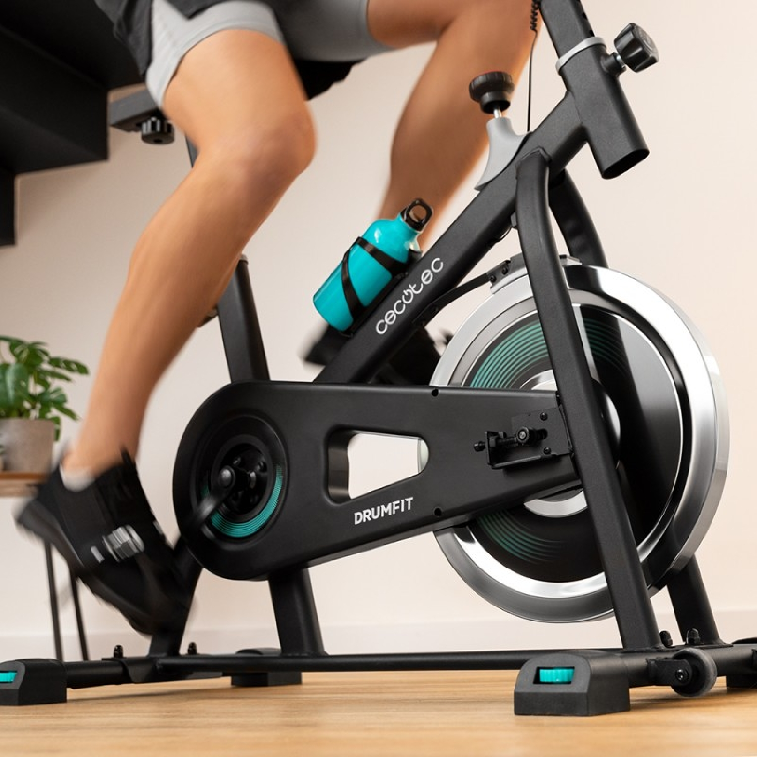 Una persona che va in bicicletta su una cyclette nera. Una bottiglia d'acqua è sulla bici.