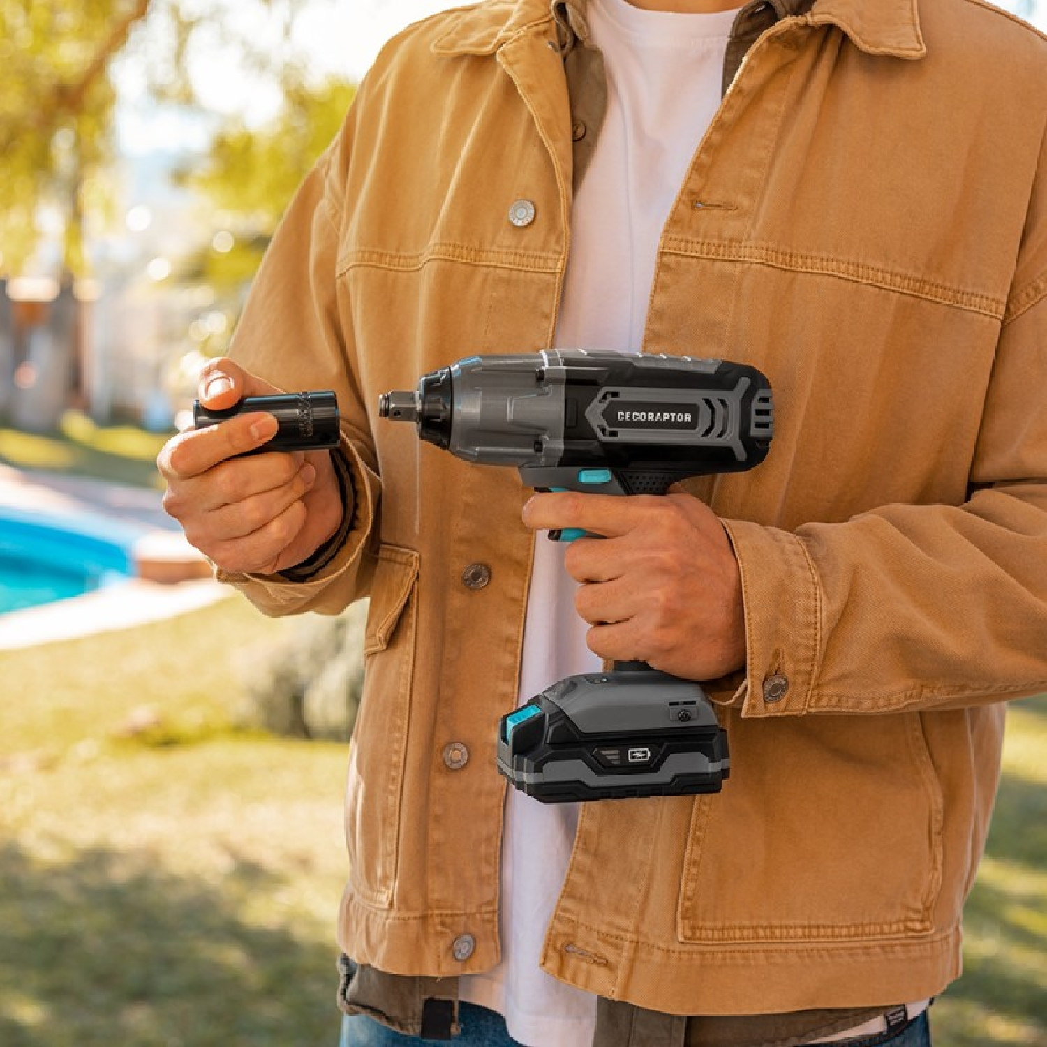 Mężczyzna trzyma czarno-szare elektronarzędzie, z czarną nasadką w ręku.