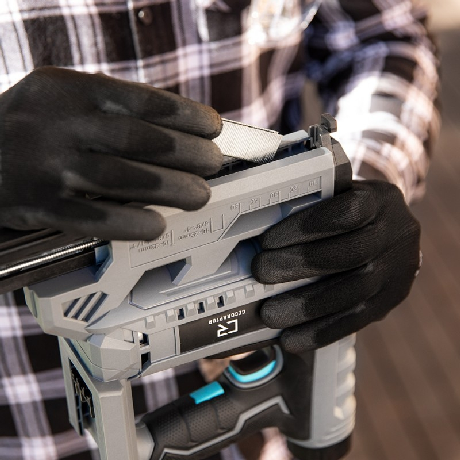 Person using a staple gun, with black gloves. The tool is gray and black.