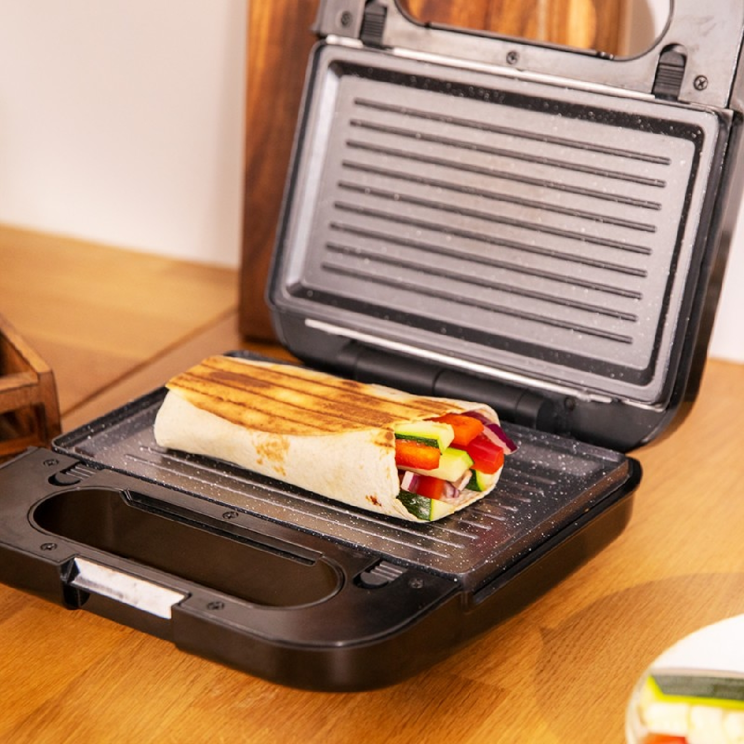 Sandwichmaker met een gegrilde wrap gevuld met groenten.