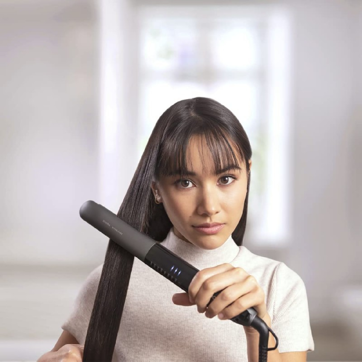 Kobieta używa prostownicy do włosów.