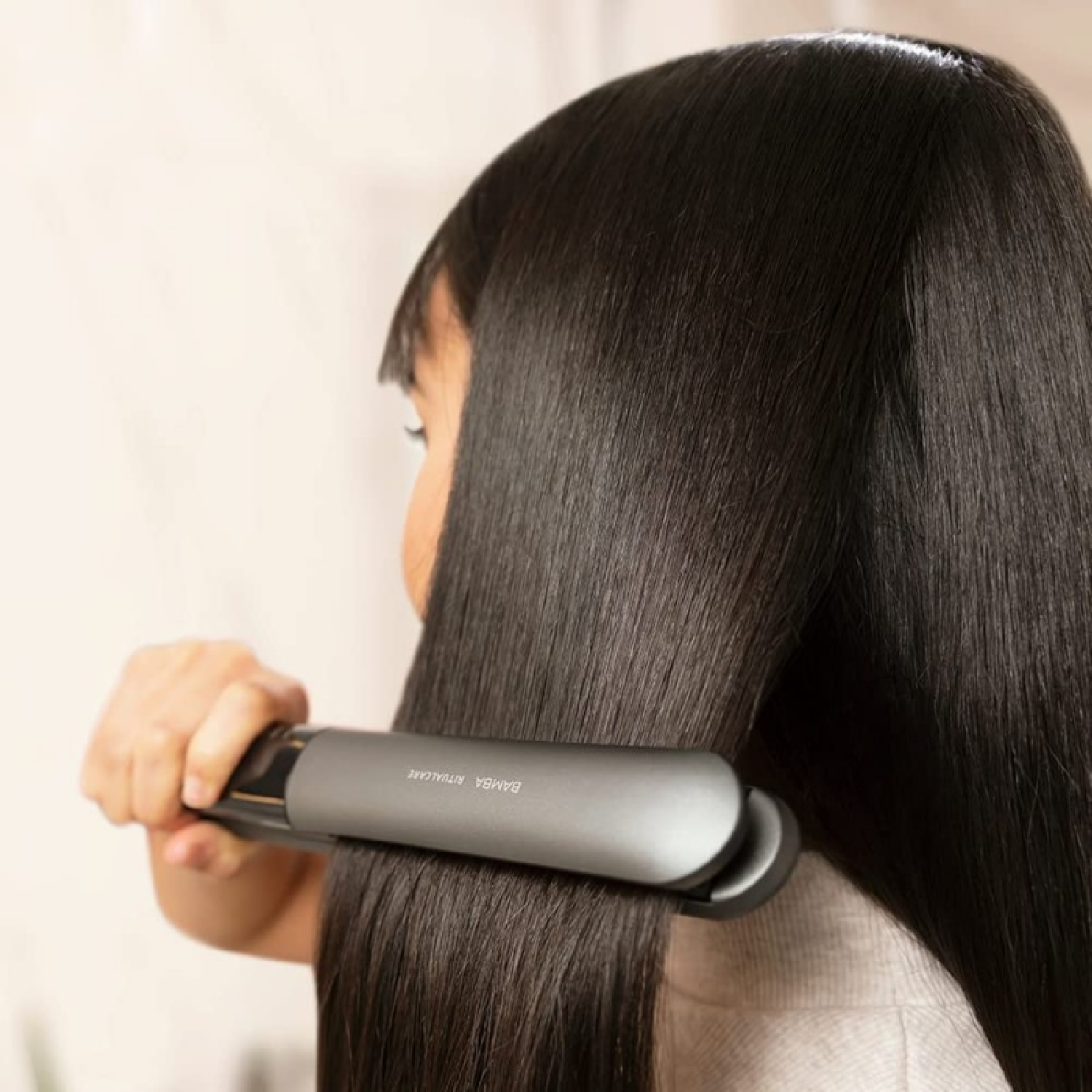 Persona che usa una piastra per capelli su capelli neri lunghi e lisci.