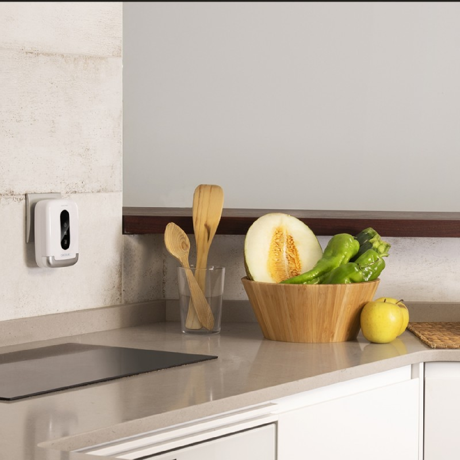 Escena de cocina: electrodoméstico blanco en la pared, fruta en un cuenco, cucharas de madera en un vaso.