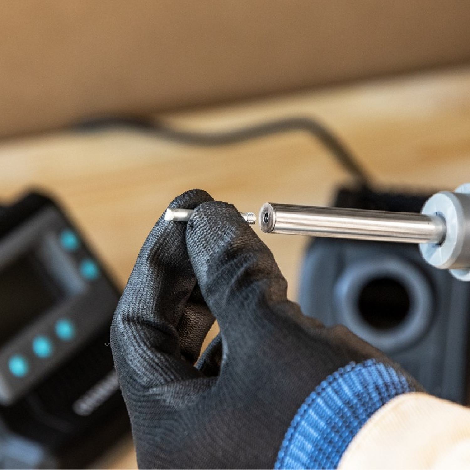 Ręka trzymająca śrubę i śrubokręt. Znajduje się przed urządzeniem elektronicznym.