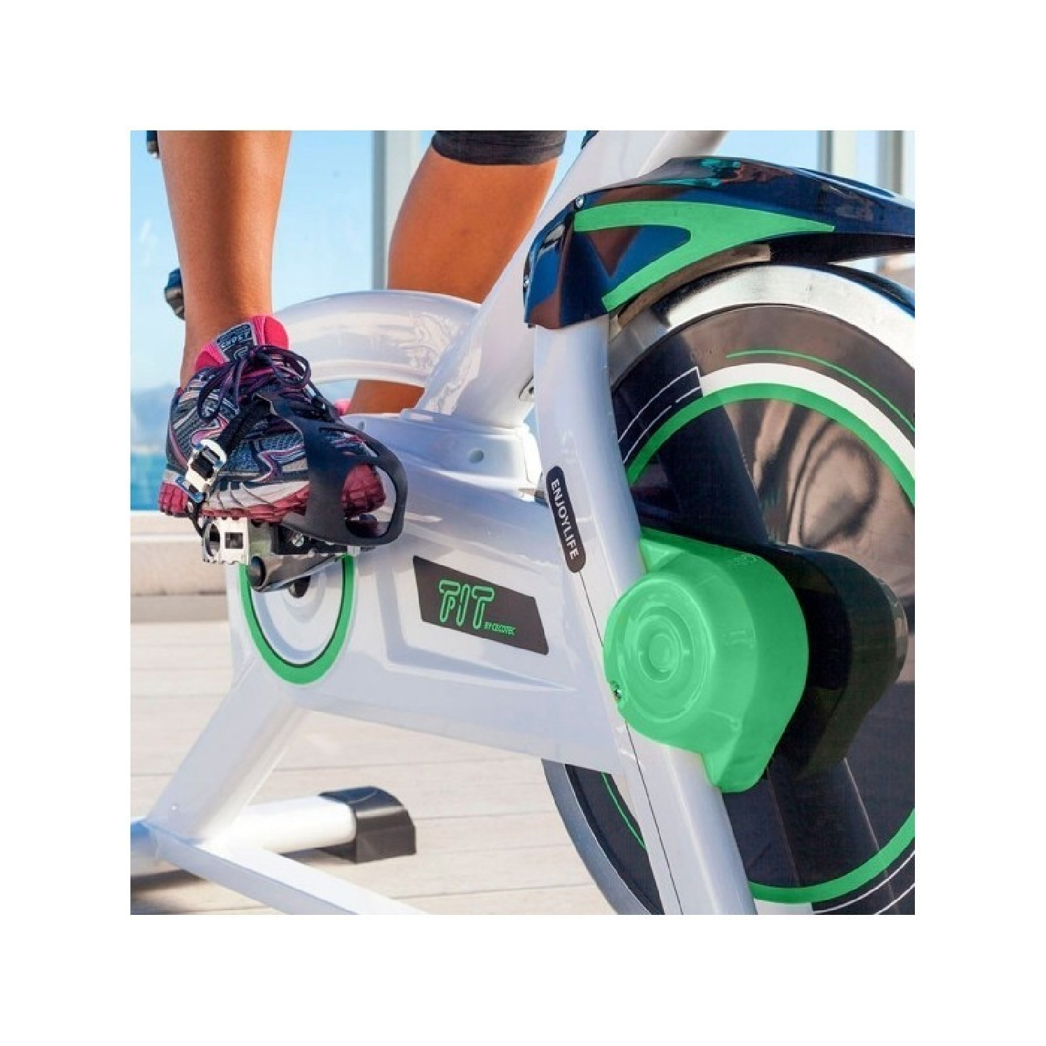 Pierna y pie de una persona en una bicicleta estática blanca y verde.