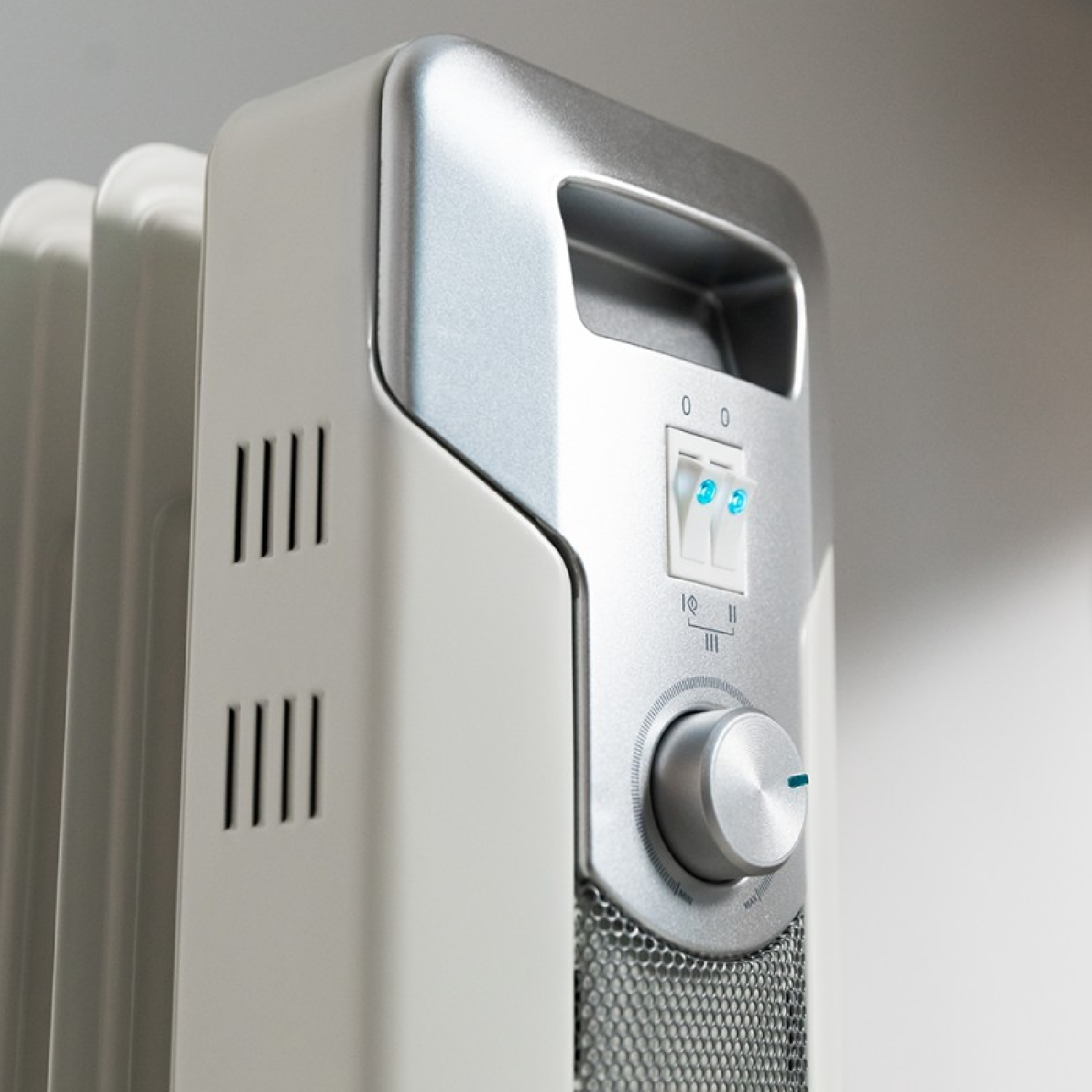 Biały grzejnik ze srebrną górą i pokrętłem sterowania.