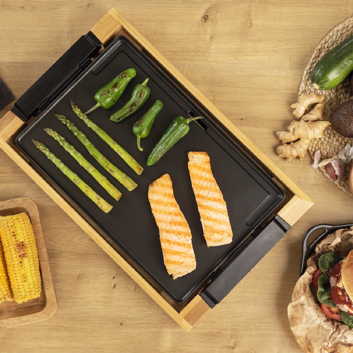 Una griglia con salmone, peperoni verdi, asparagi e mais sopra. Superficie in legno.