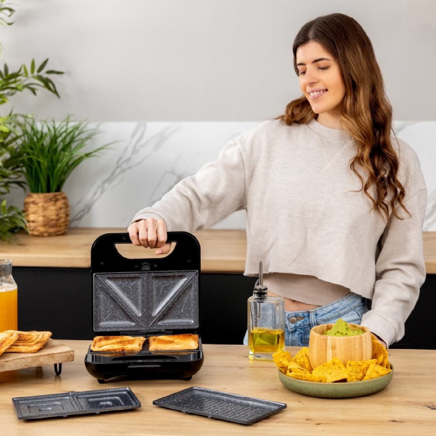 Donna apre sandwich maker con toast. Cucina con snack.