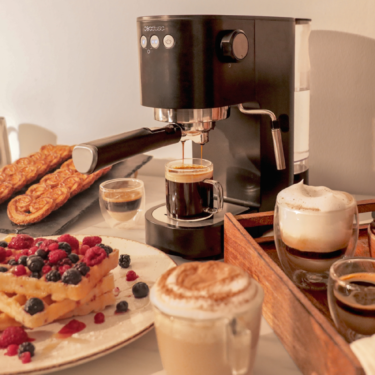 Espressomaschine mit Kaffee, der in eine Tasse gegossen wird. Waffeln, Gebäck und Kaffeegetränke in der Nähe.