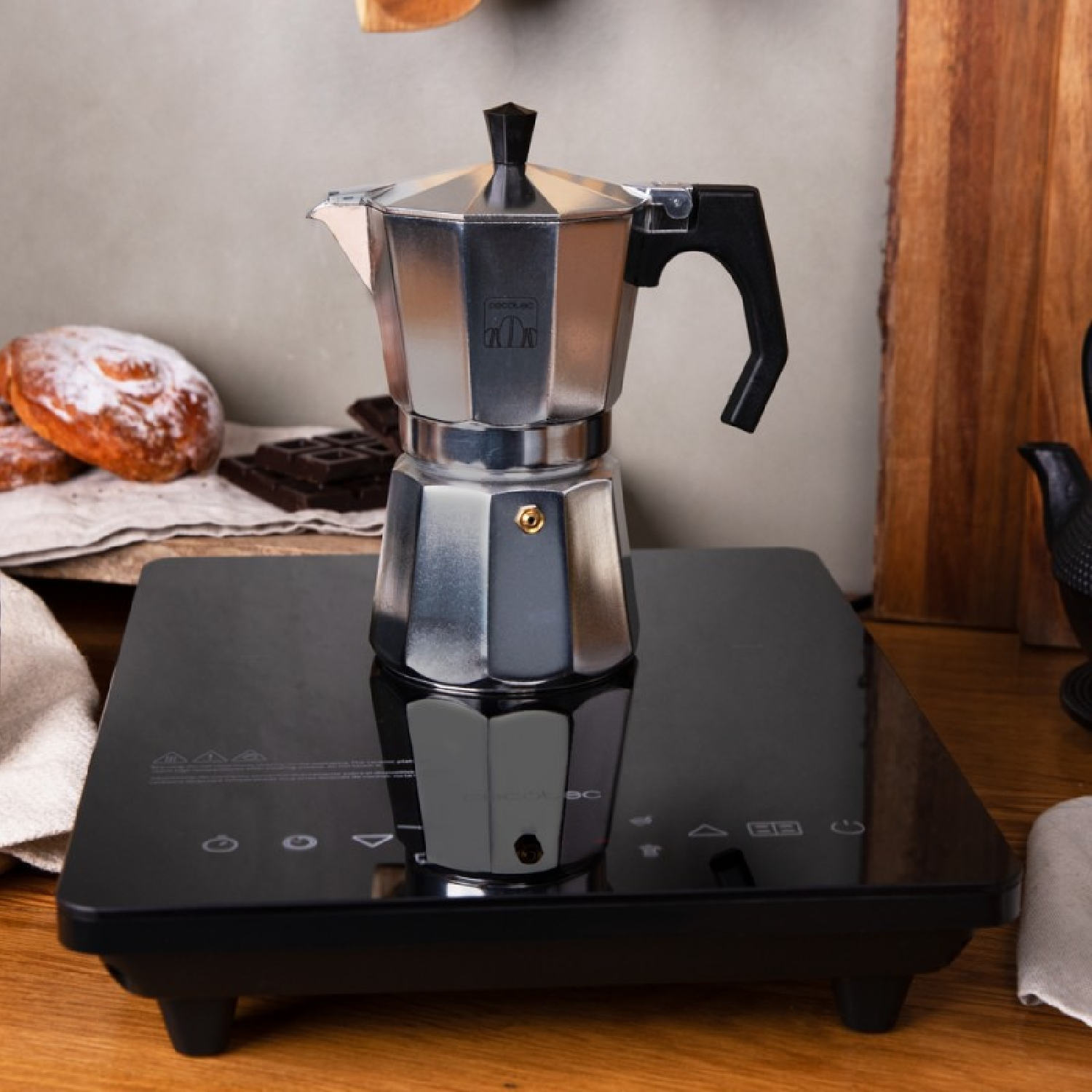 Srebrny ekspres do espresso na czarnej płycie indukcyjnej.