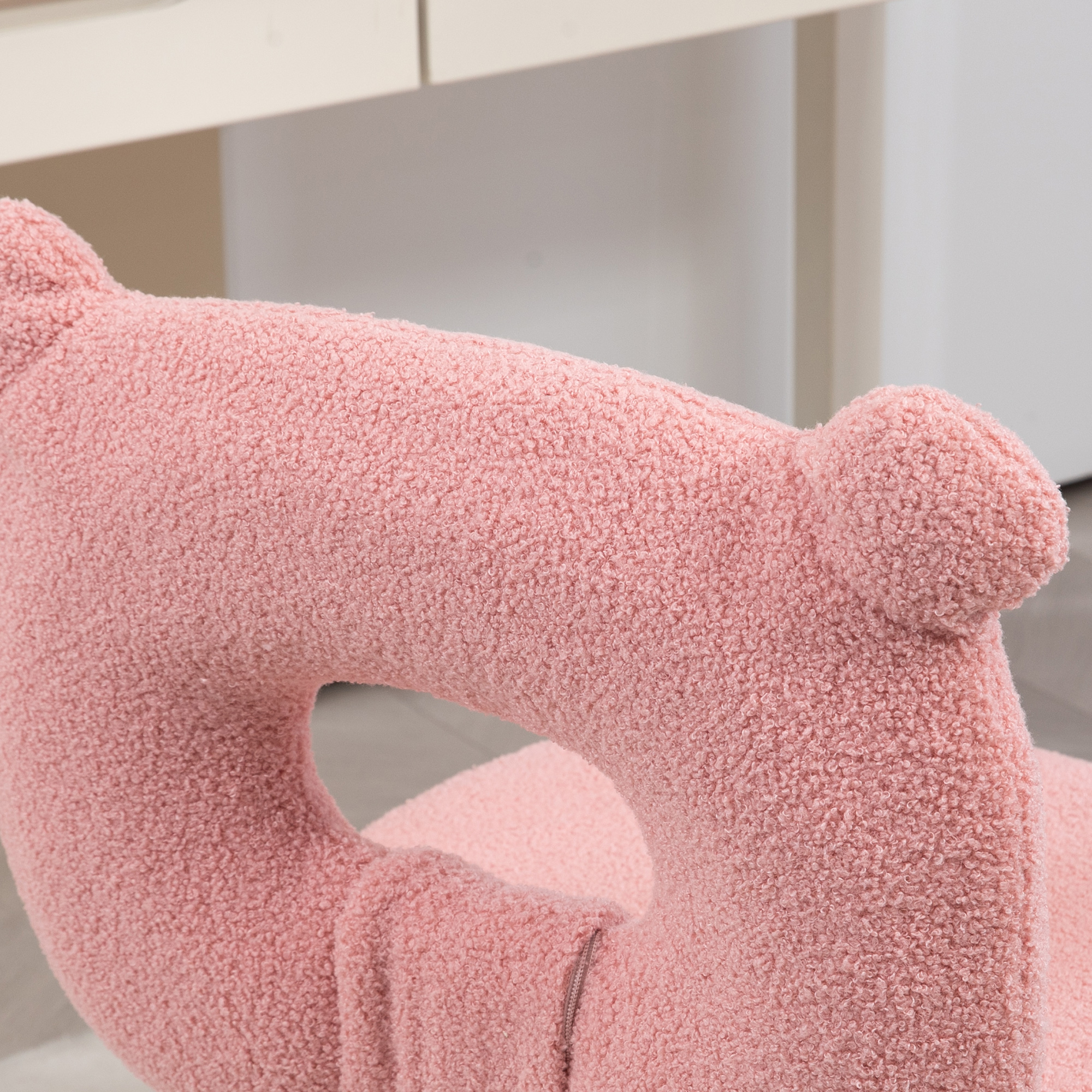 Primer plano de un respaldo de silla rosa y esponjoso con forma curva y un agujero. Es de color rosa claro.