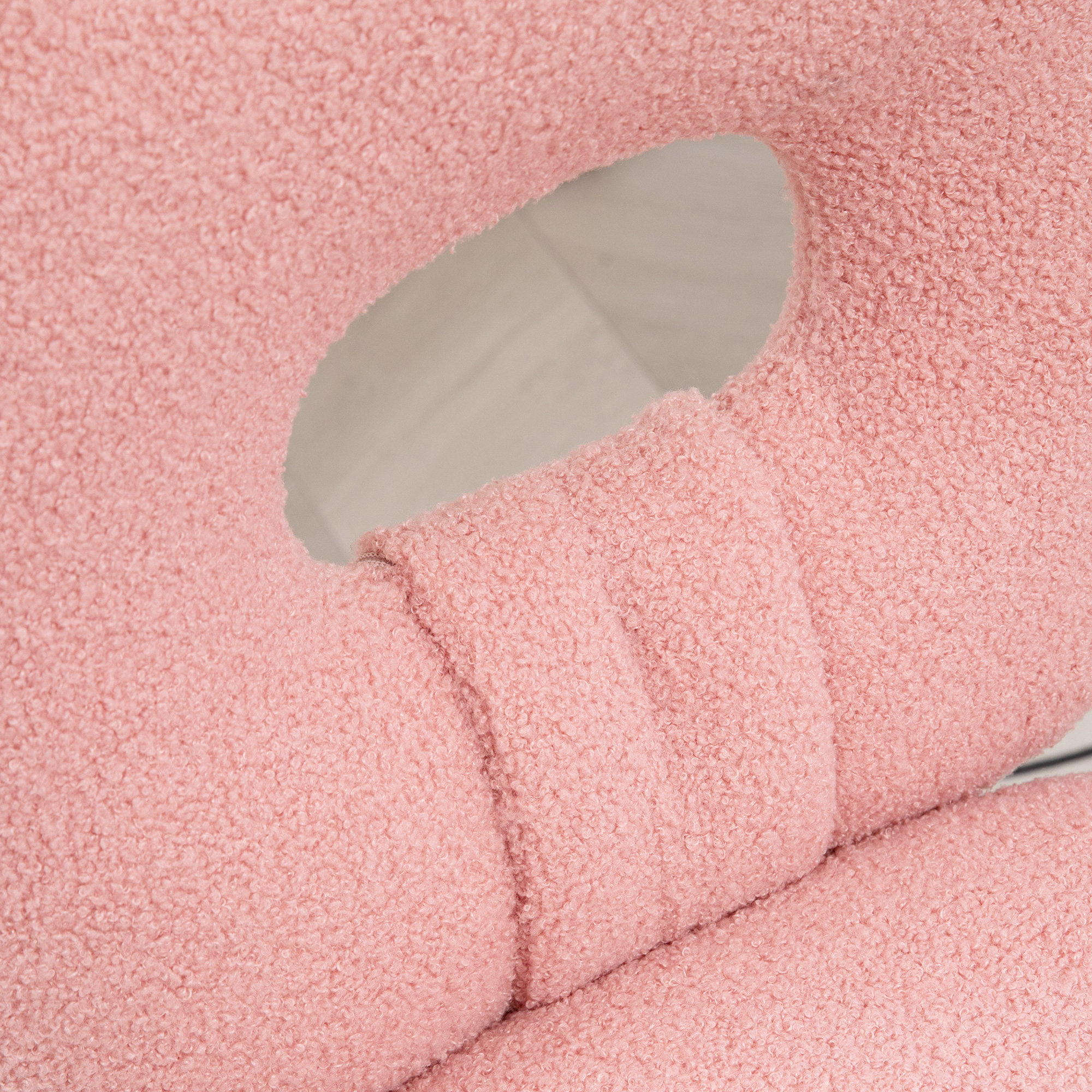 Primer plano de una almohada rosa y texturizada con un agujero en el centro.