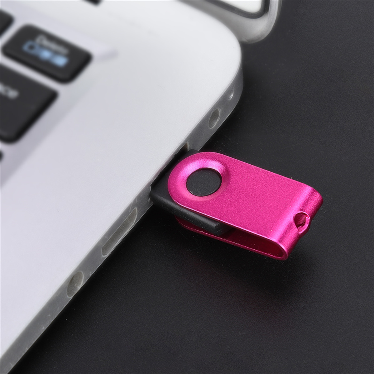 Ein rosa USB-Stick, der in einen silbernen Laptop eingesteckt ist. Der Stick steckt im USB-Anschluss an der Seite.