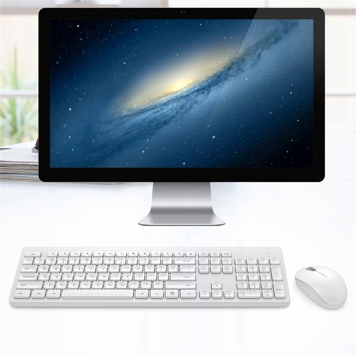 Desktop-Setup. Computer mit Galaxiehintergrund, weiße Tastatur und Maus.