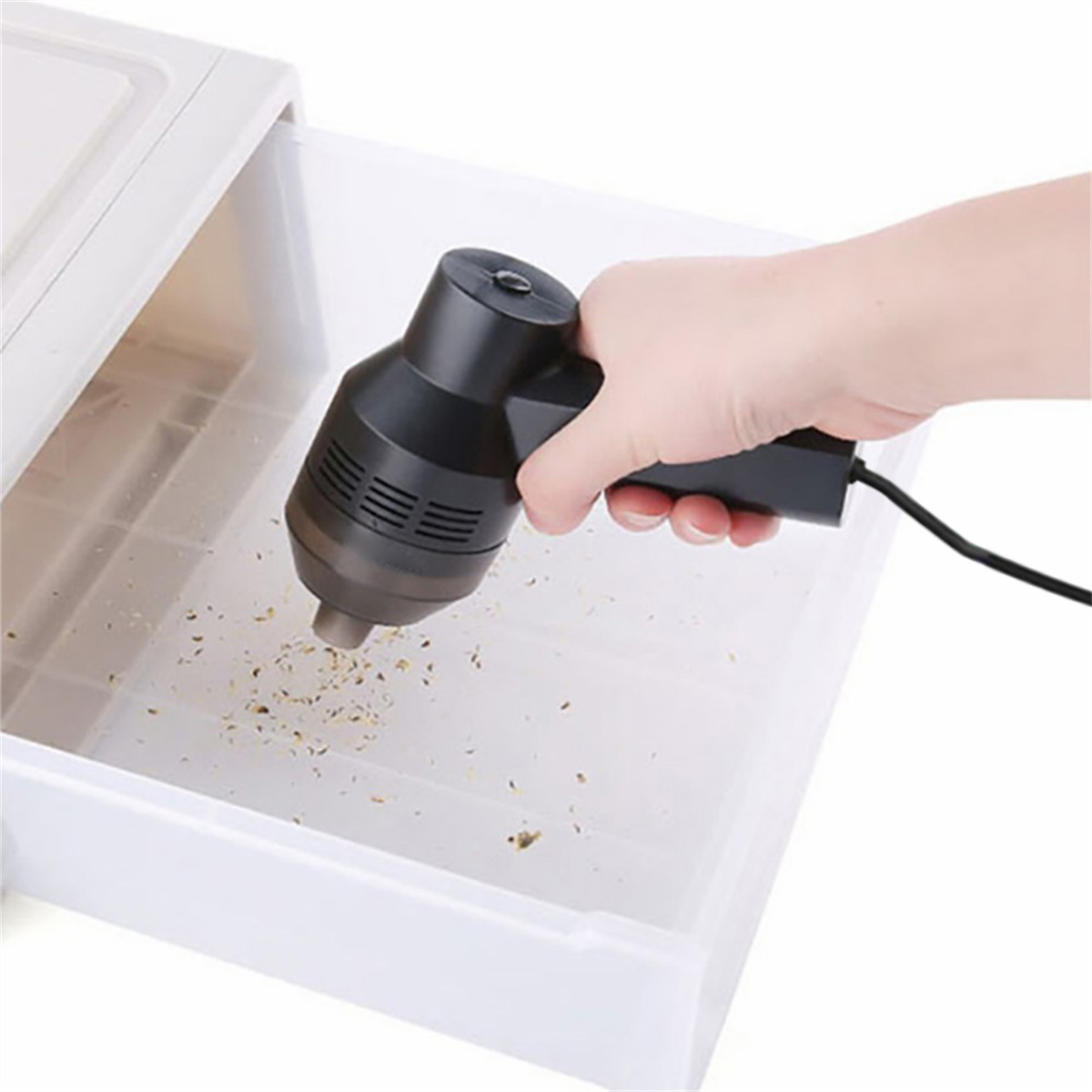 Hand, die einen schwarzen Staubsauger benutzt, um eine Schublade zu reinigen.