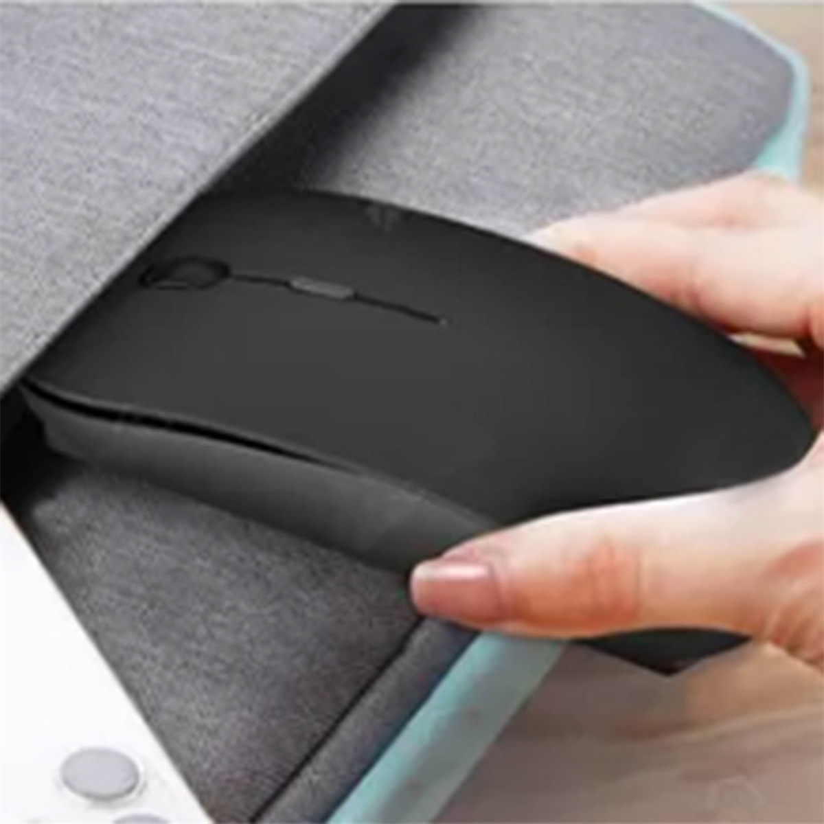 Hand legt eine schwarze Computermaus in eine graue Laptop-Hülle.