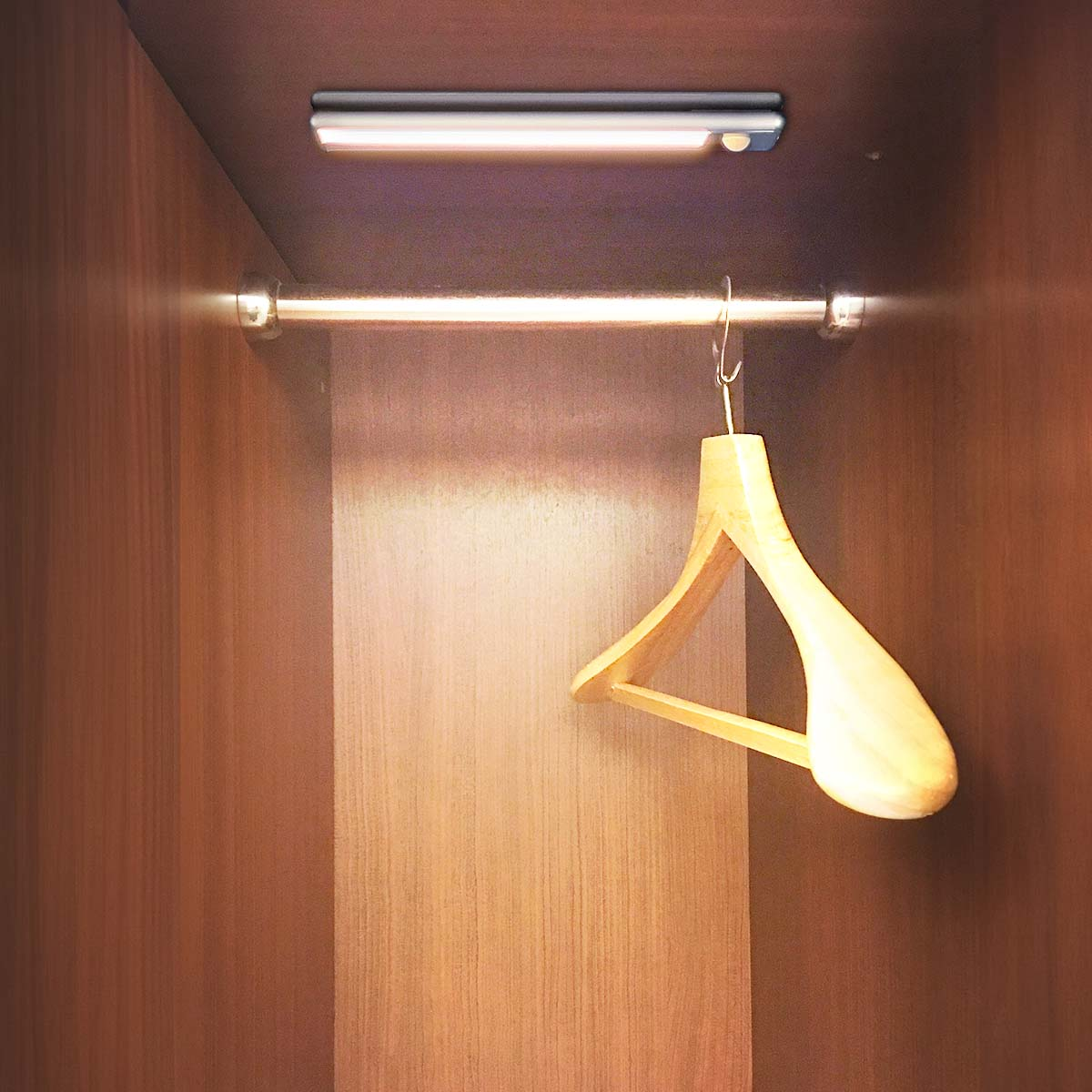 A wooden hanger inside a closet. A light strip is above. The closet is wooden.