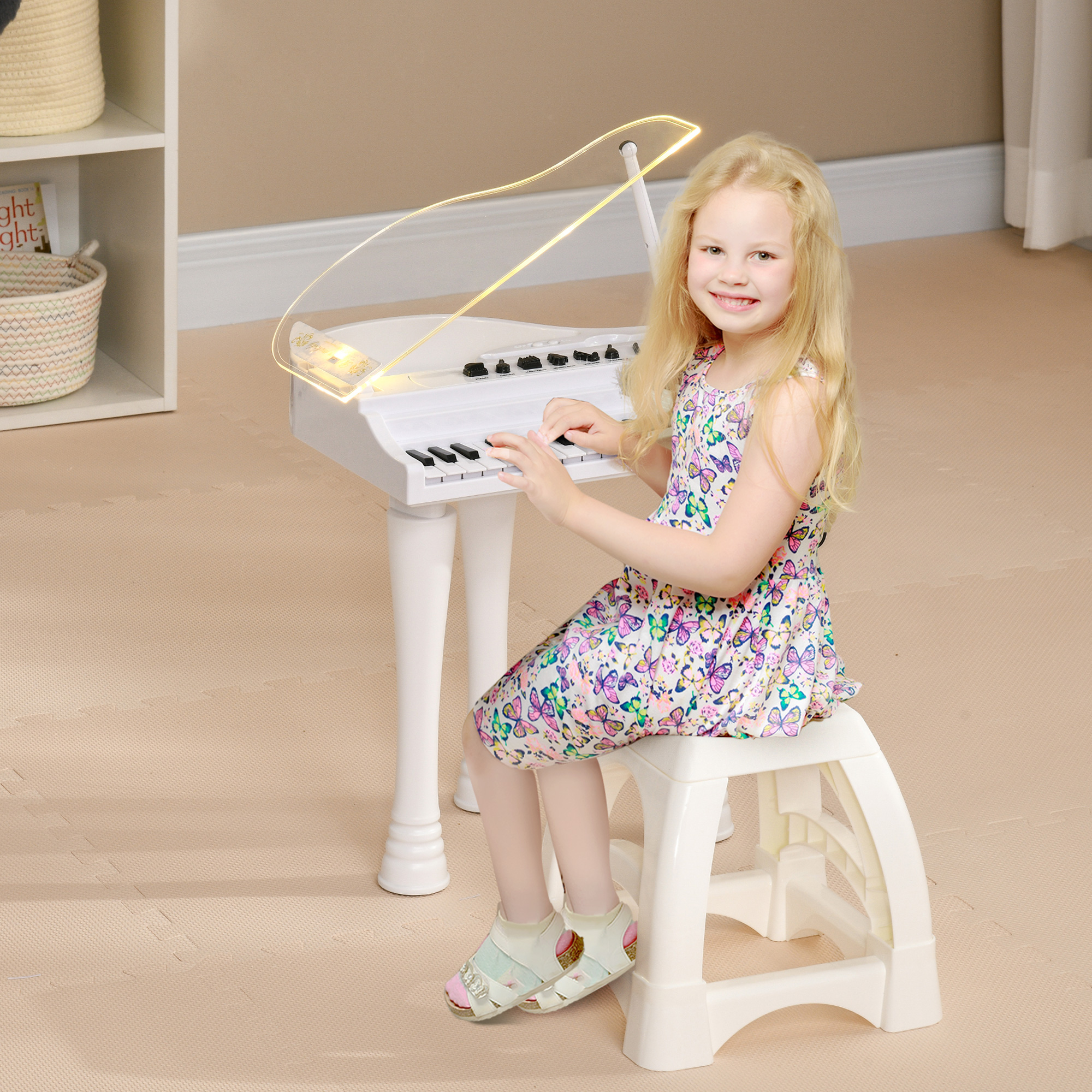 Una niña sonriente tocando un piano de juguete blanco con una luz encima.