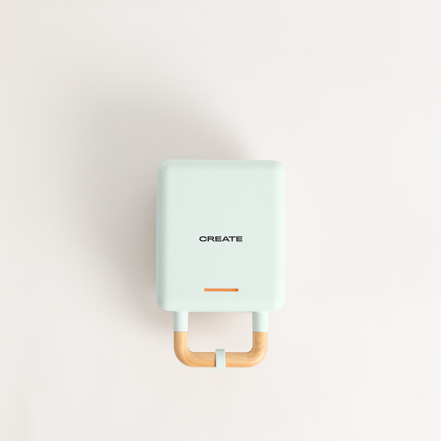 Una gofrera de color menta con mango de madera. La palabra "CREATE" está en la parte delantera.